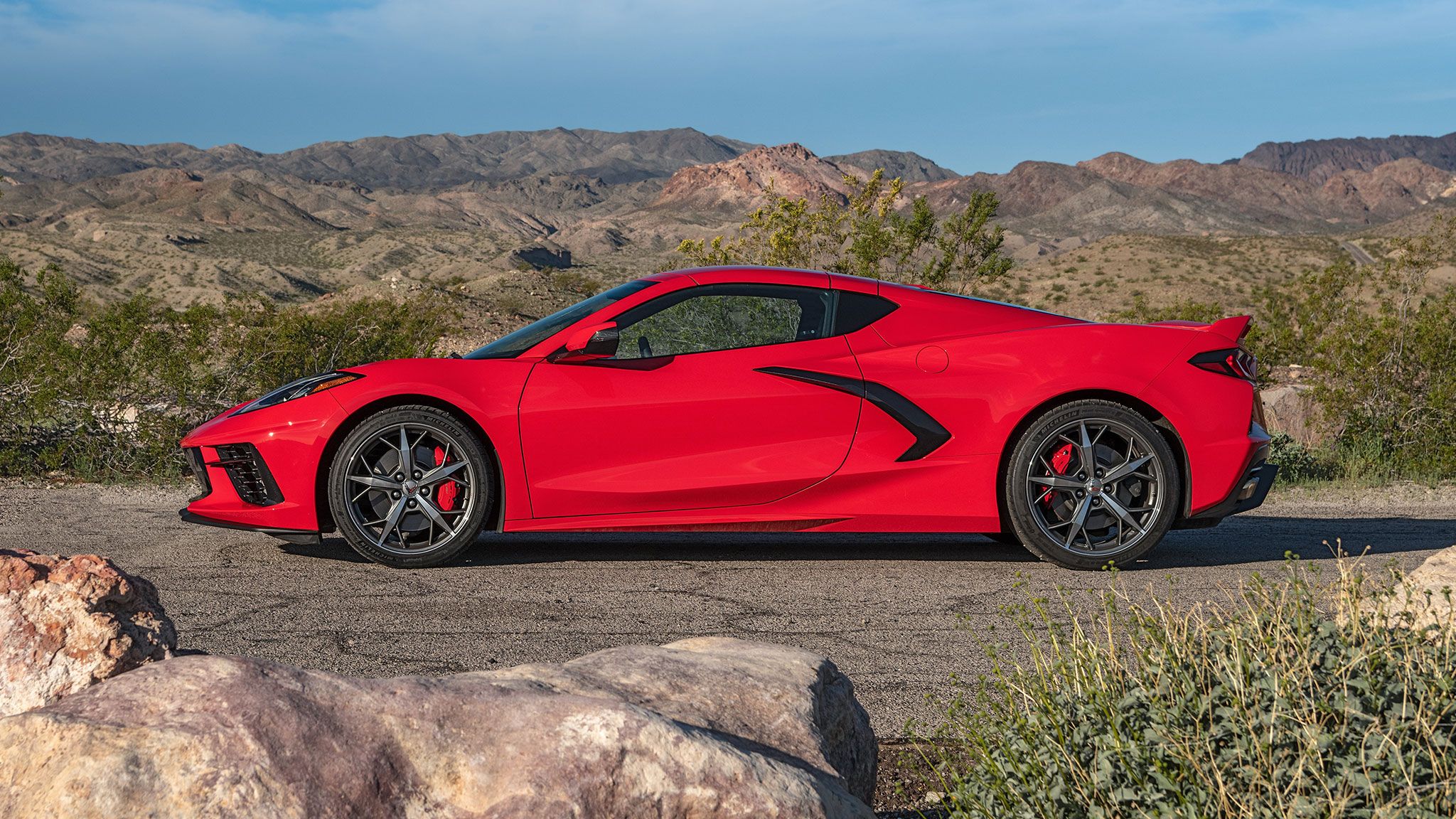 A red 2021 Chevrolet Corvette C8 stands parked on a road near the dessert.