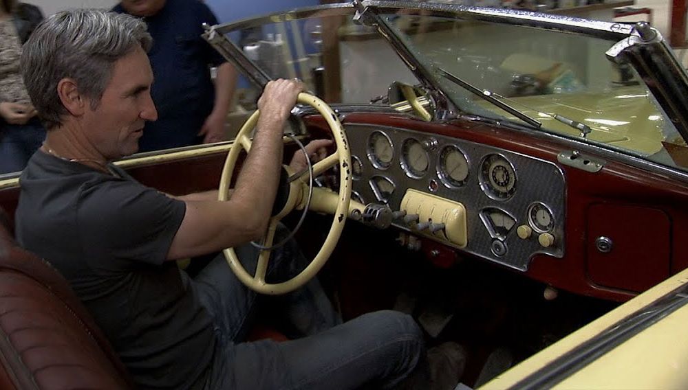 American Pickers Mike Wolfe behind the wheel of a vintage car