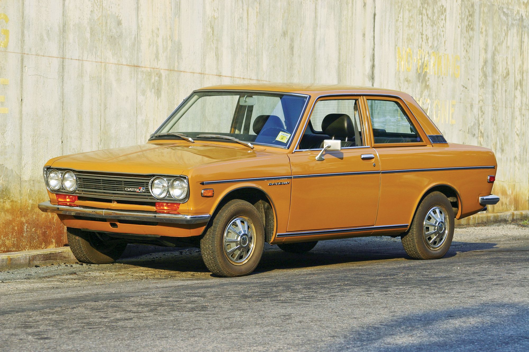 Datsun 510 from side in front of wall