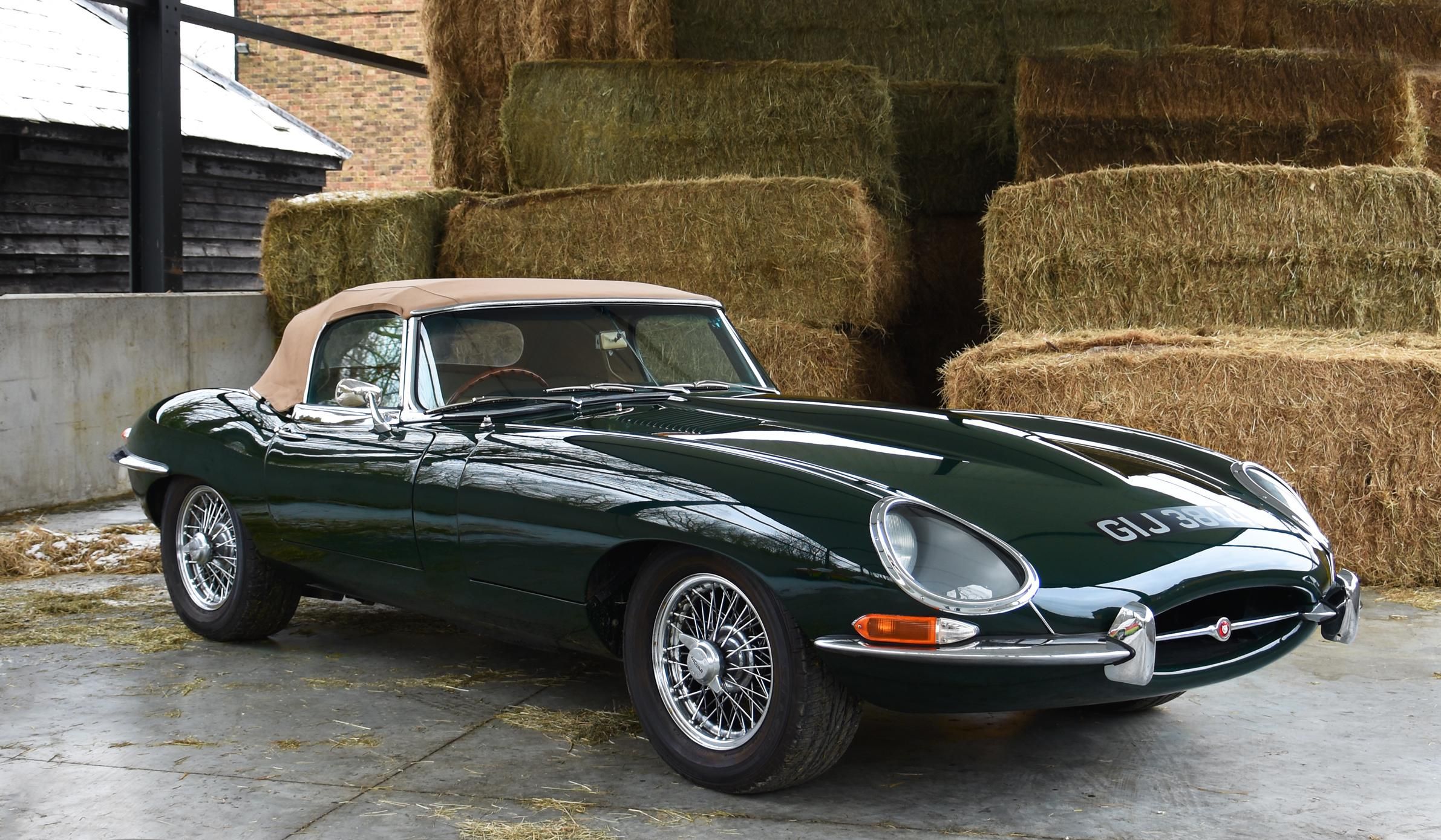 A Green Jaguar E Type in front of bales of straw