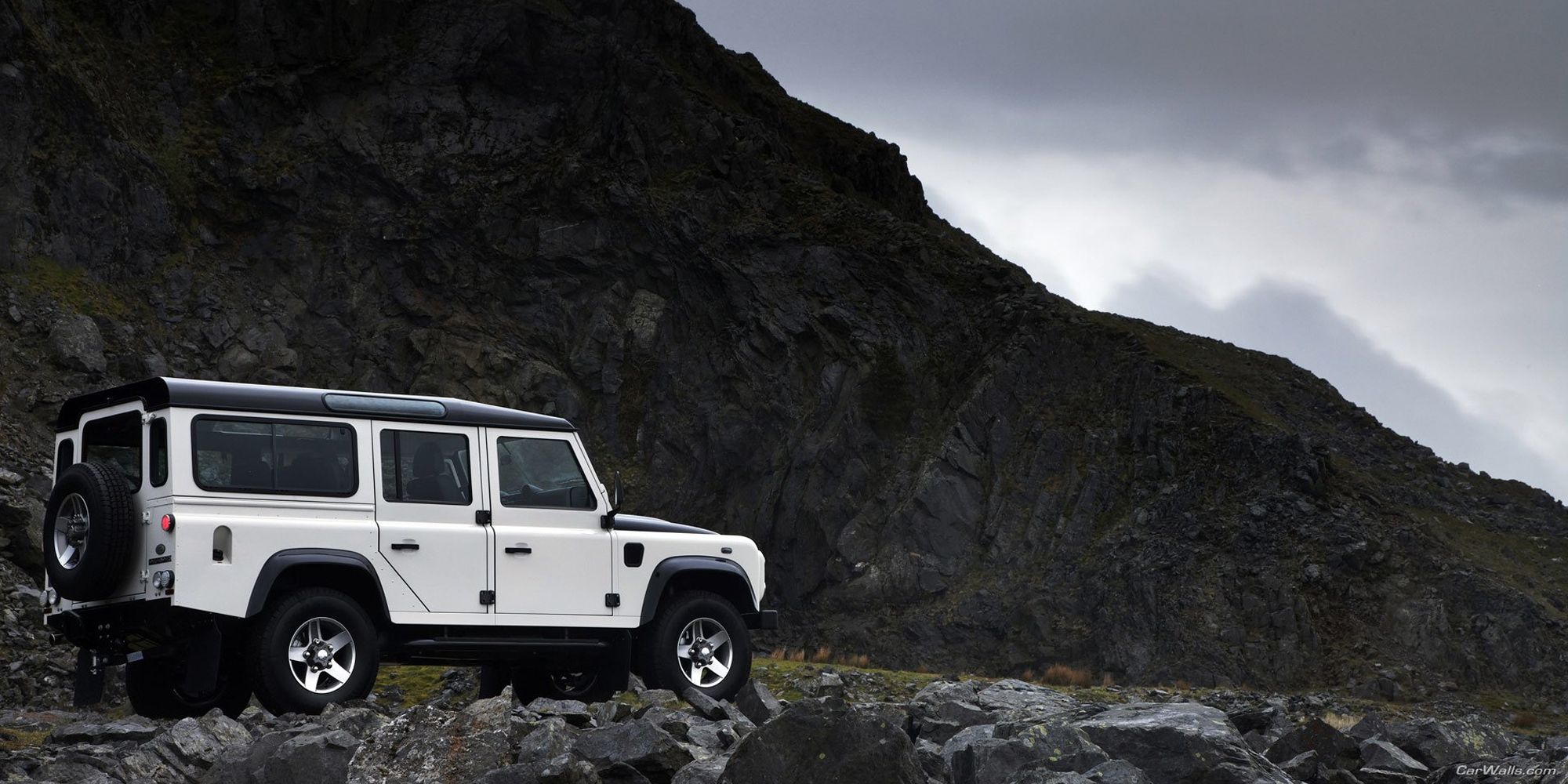 A white Defender Station Wagon in the mountains