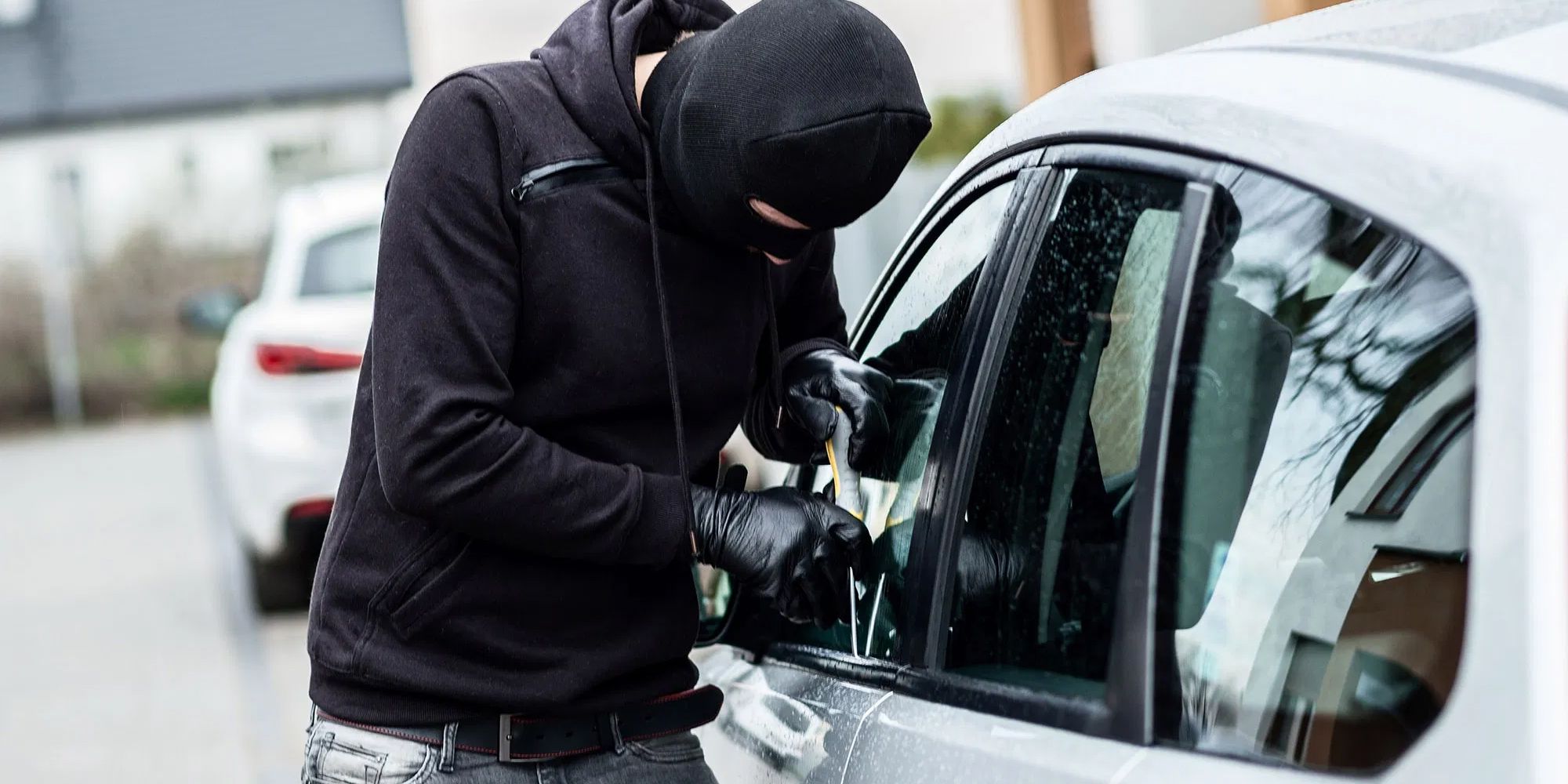 A thief attempting to break into a car