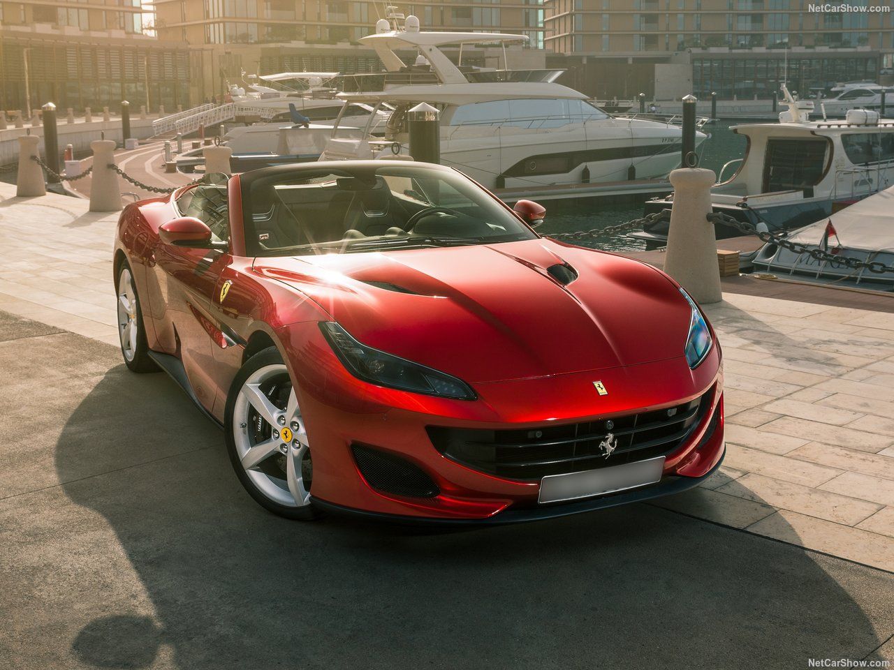 Red Ferrari Portofino parked in front of yachts
