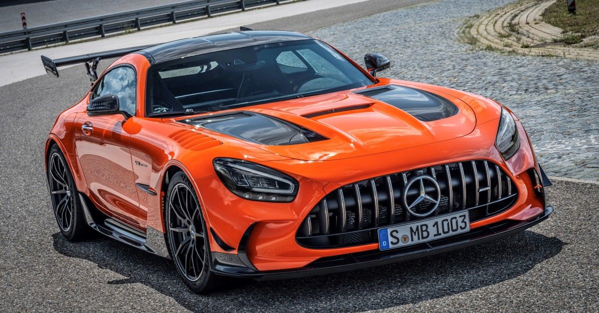 An orange Mercedes AMG GT R coupe stands parked on a road.