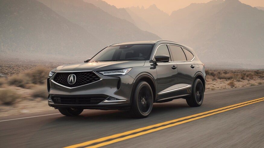 A 2022 grey Acura MDX drives down a road.
