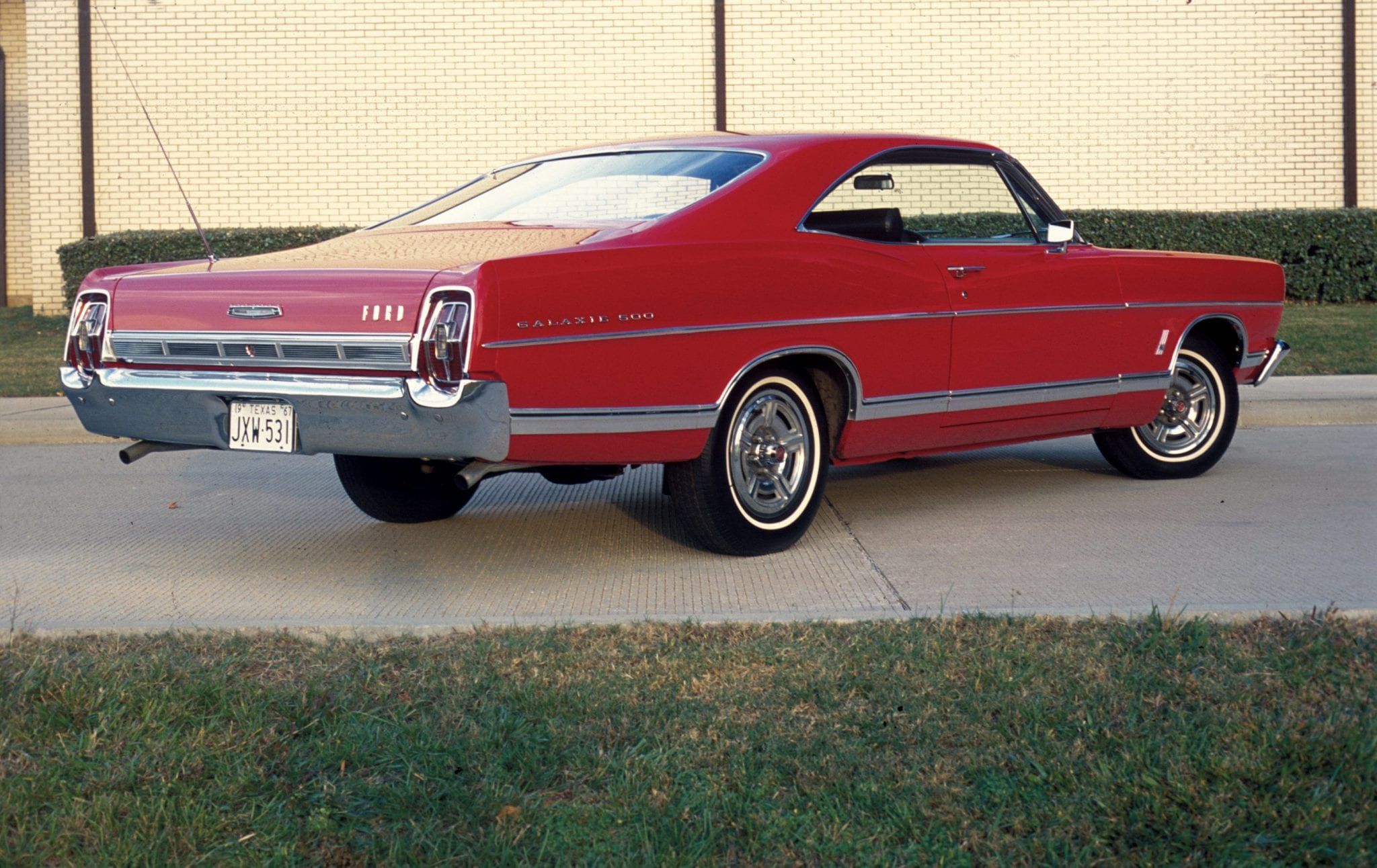 Red Ford Galaxie in driveway, back view