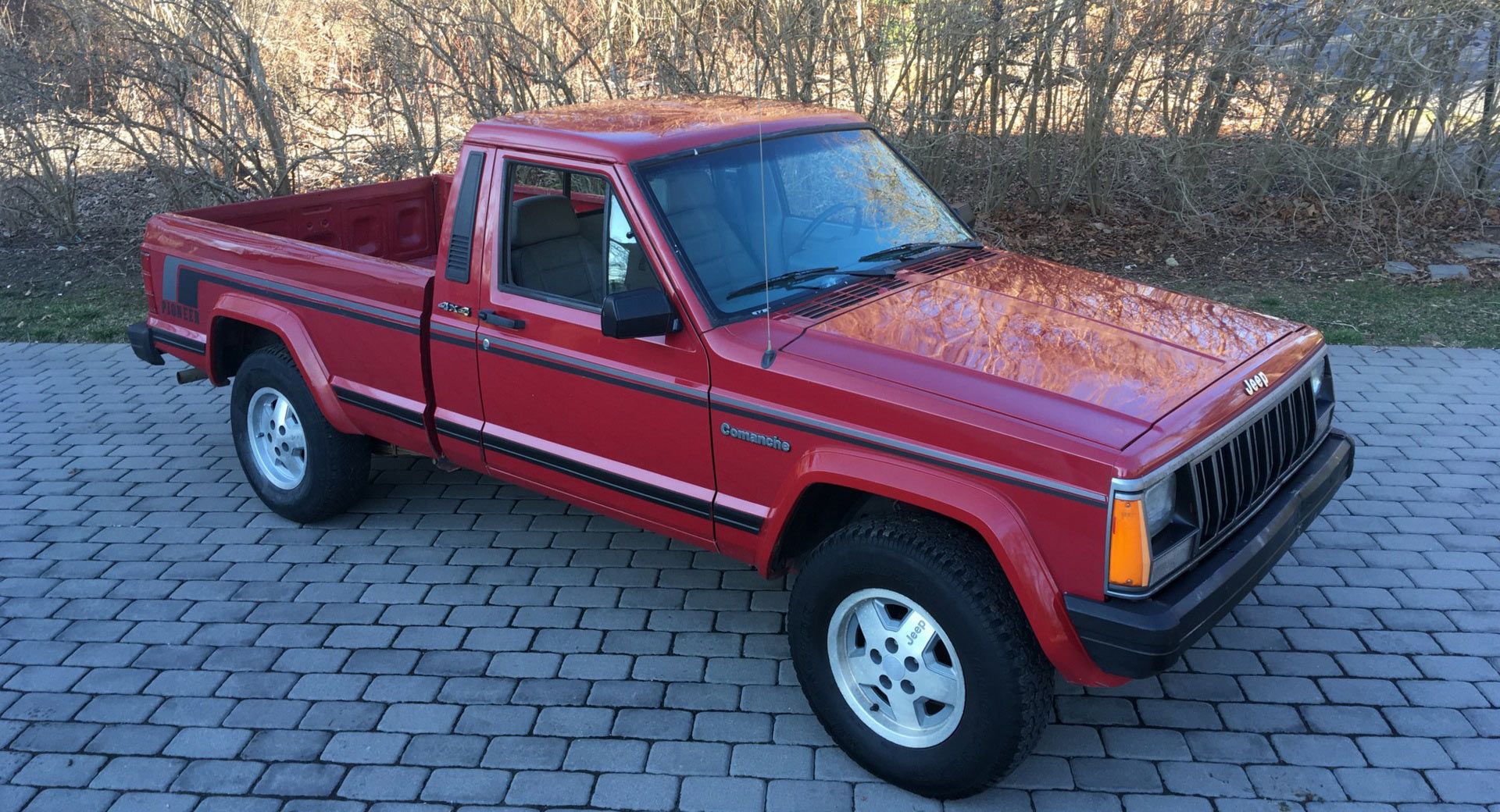Red Jeep Comanche in tile driveway