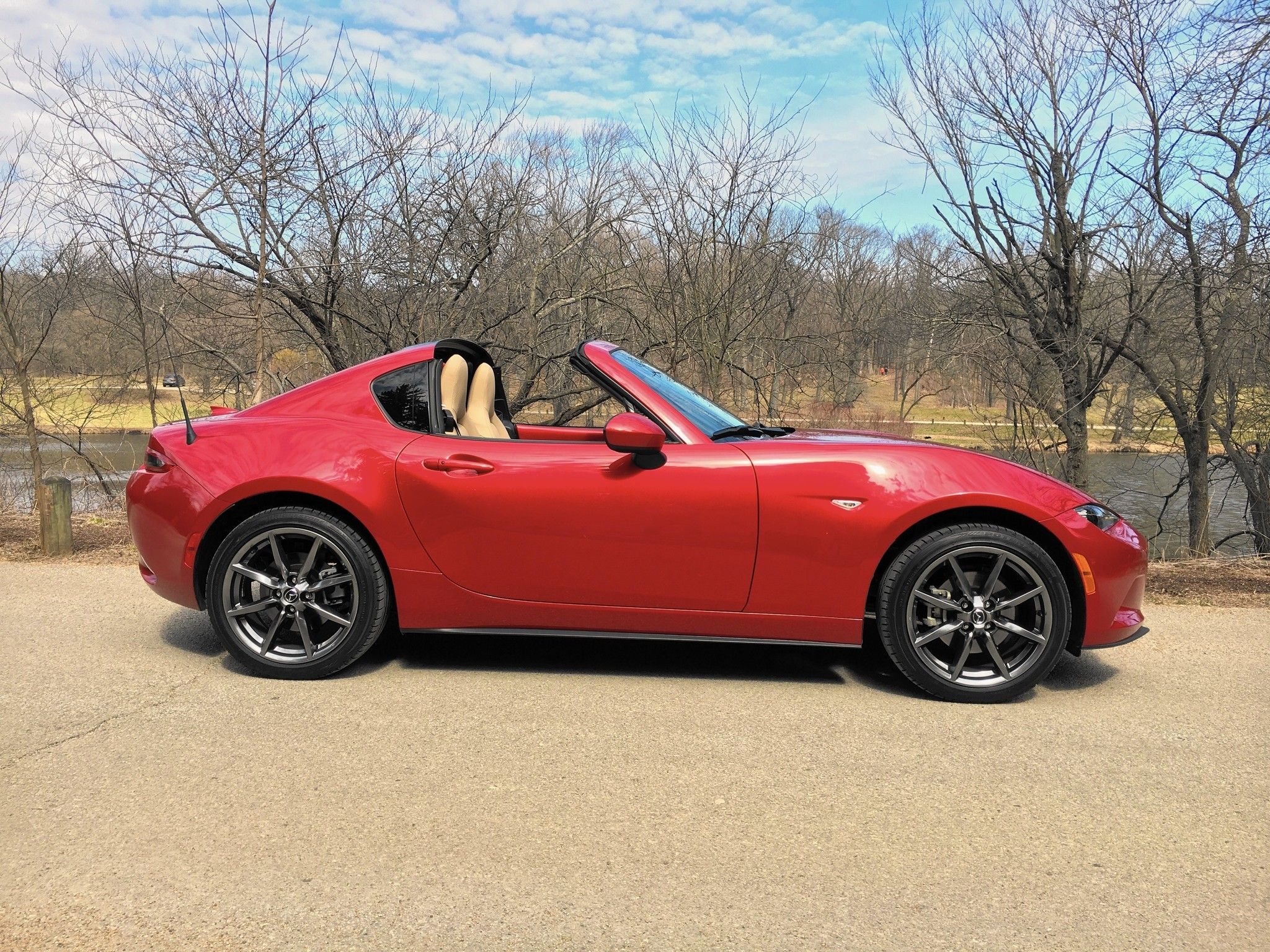 Red Mazda Miata Fastback in front of bare trees, side view
