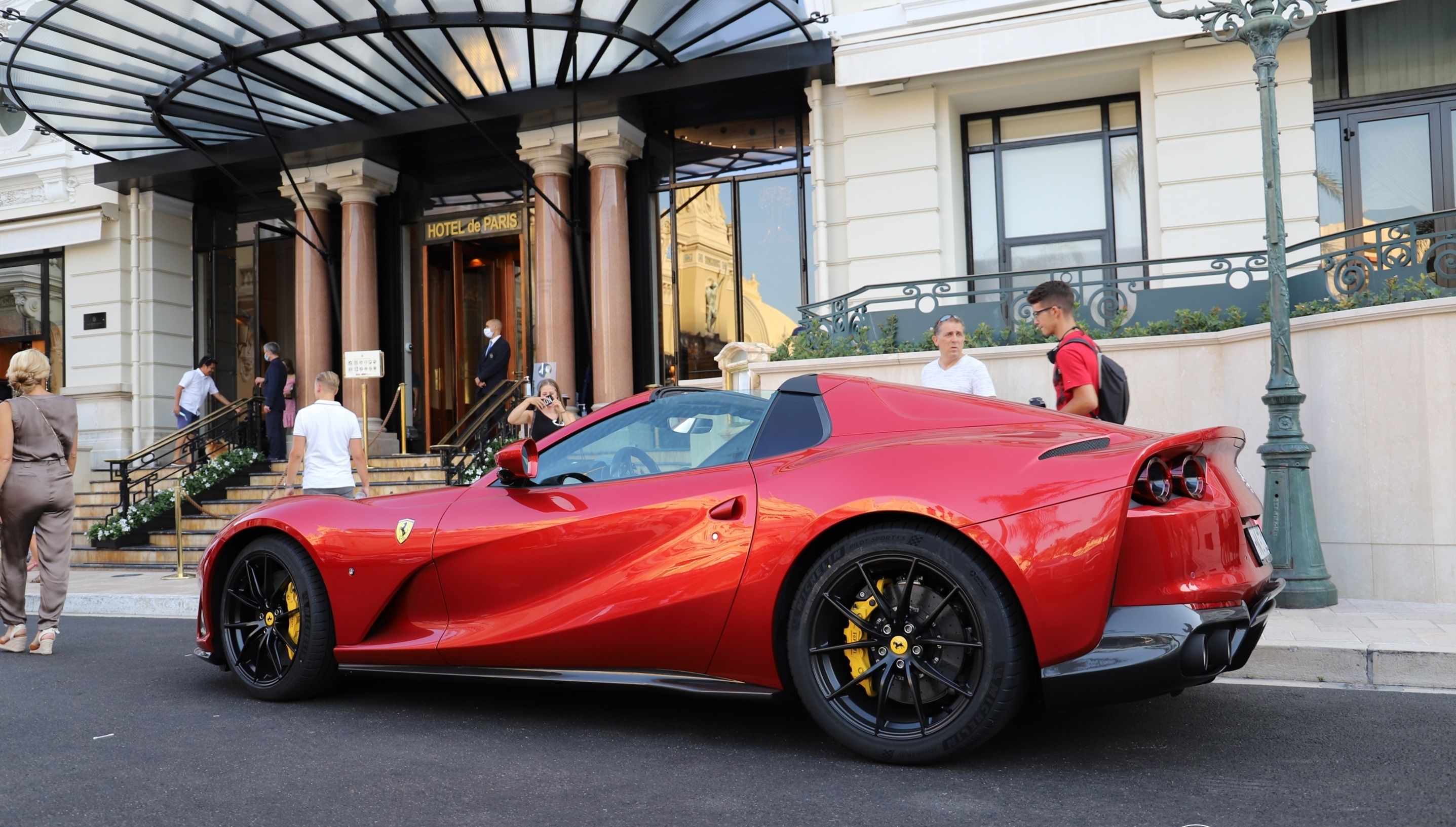 Red Ferrari 812 GTS parked in front of a hotel