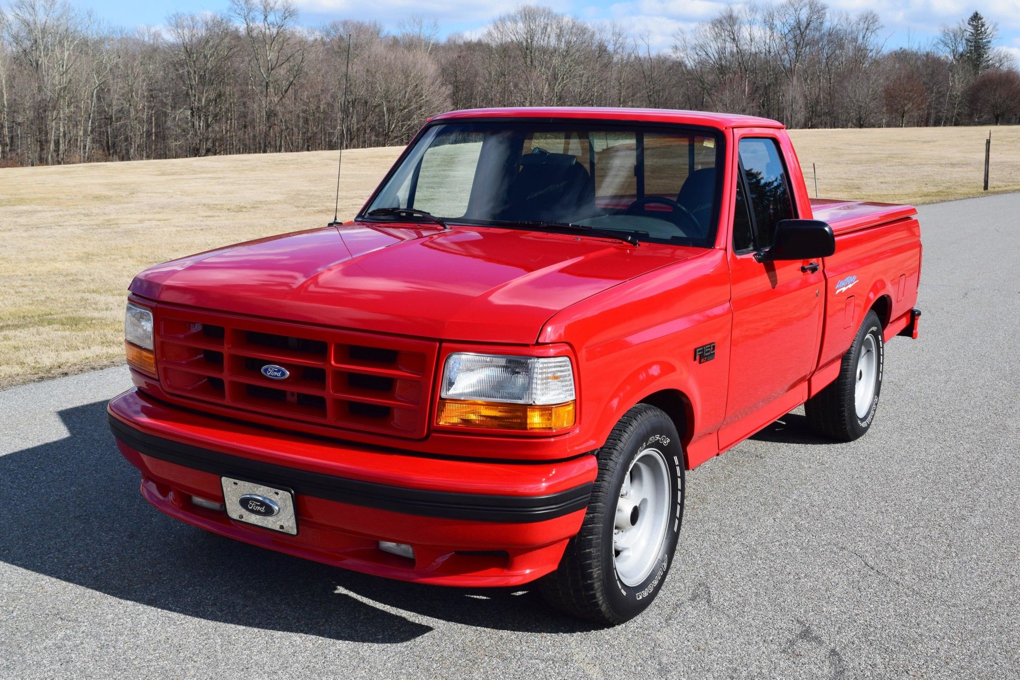 Red Ford F-150 Lightning outdoors on road