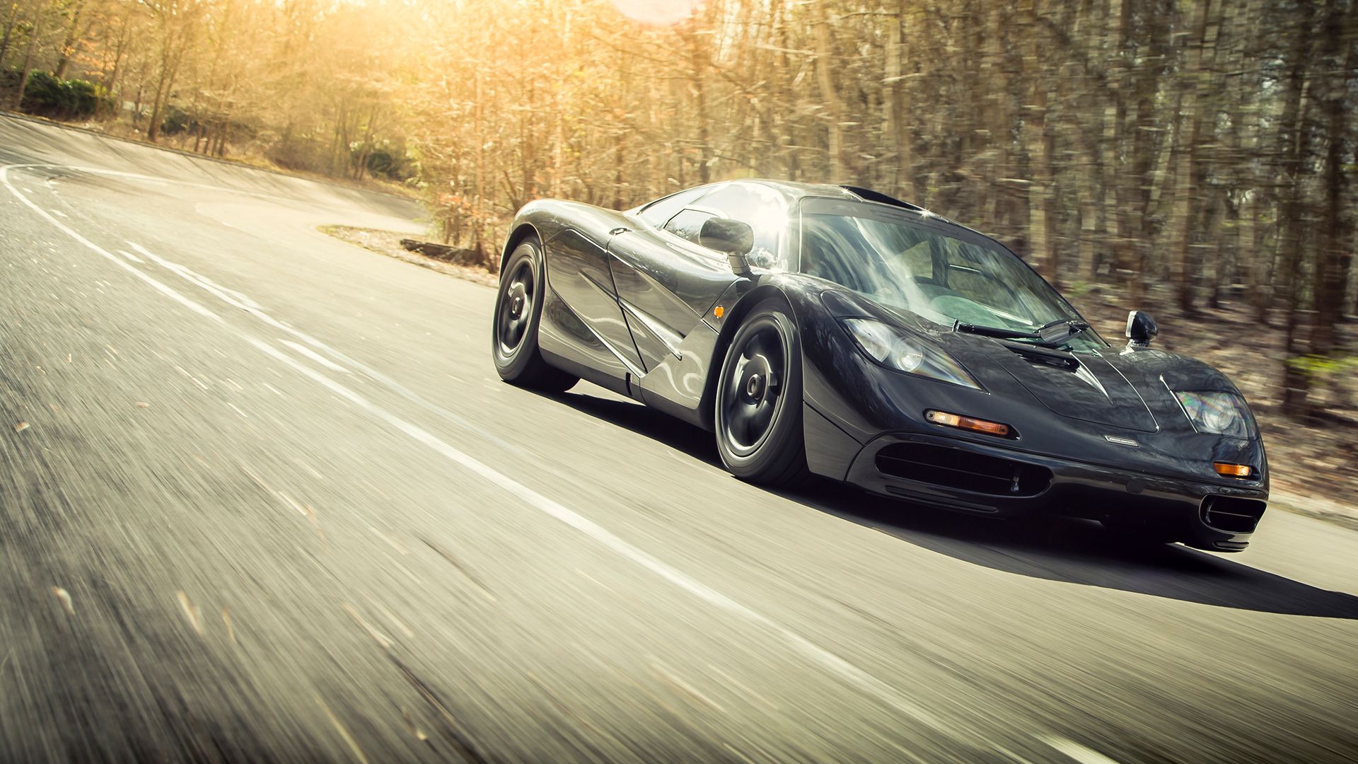 McLaren F1 driving through countryside surrounded by trees