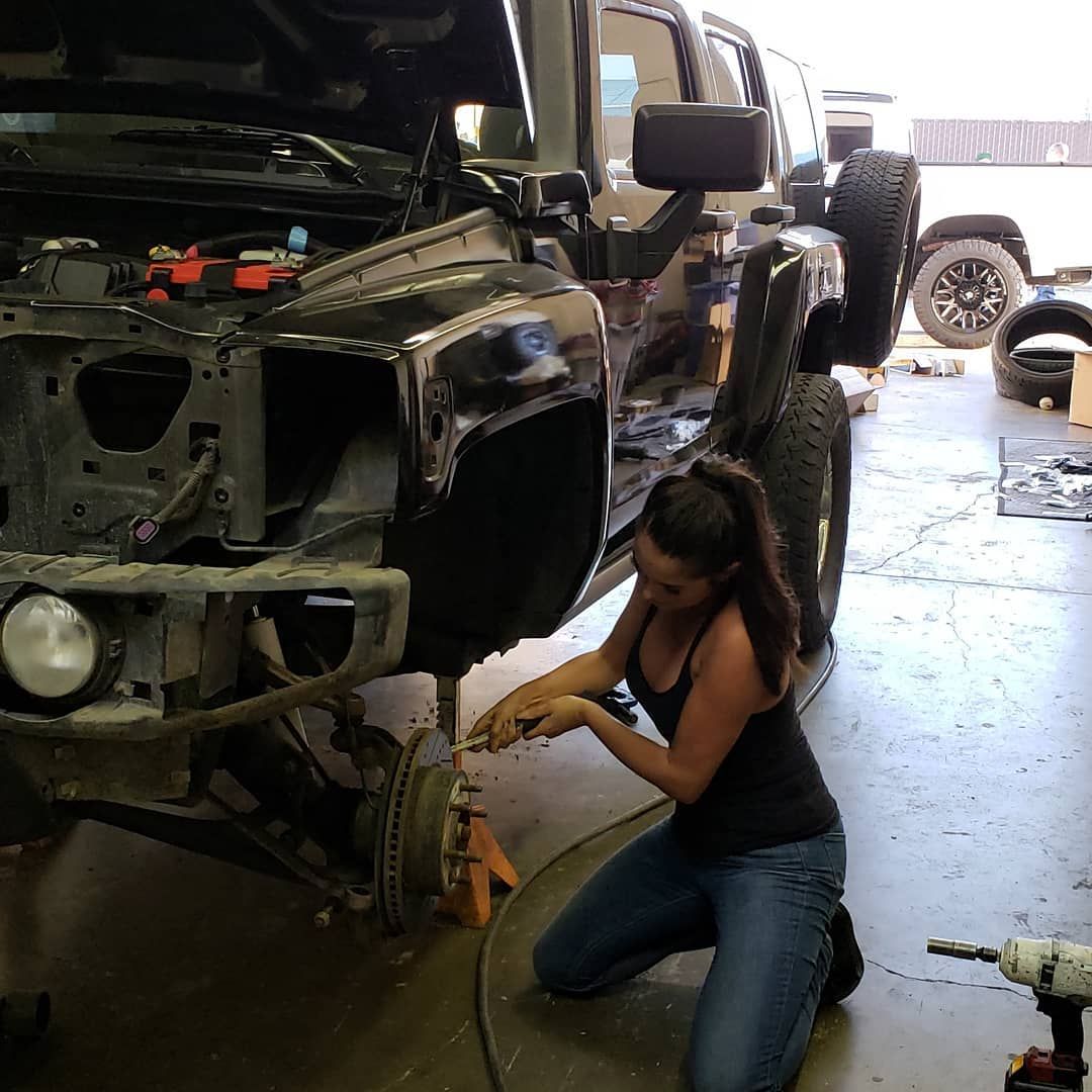 Constance Nunes fixing car, closeup of work on brake disc