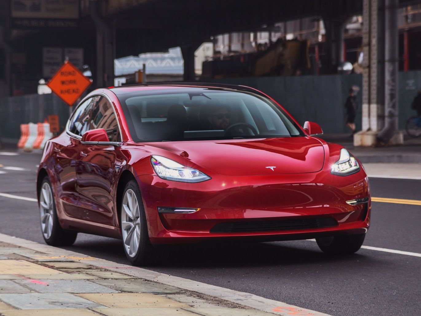 Red Tesla driving down street
