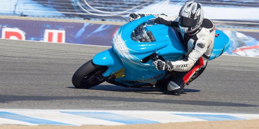 A professional rider leans hard into a turn on the Lightning LS-218 at Laguna Seca Raceway.
