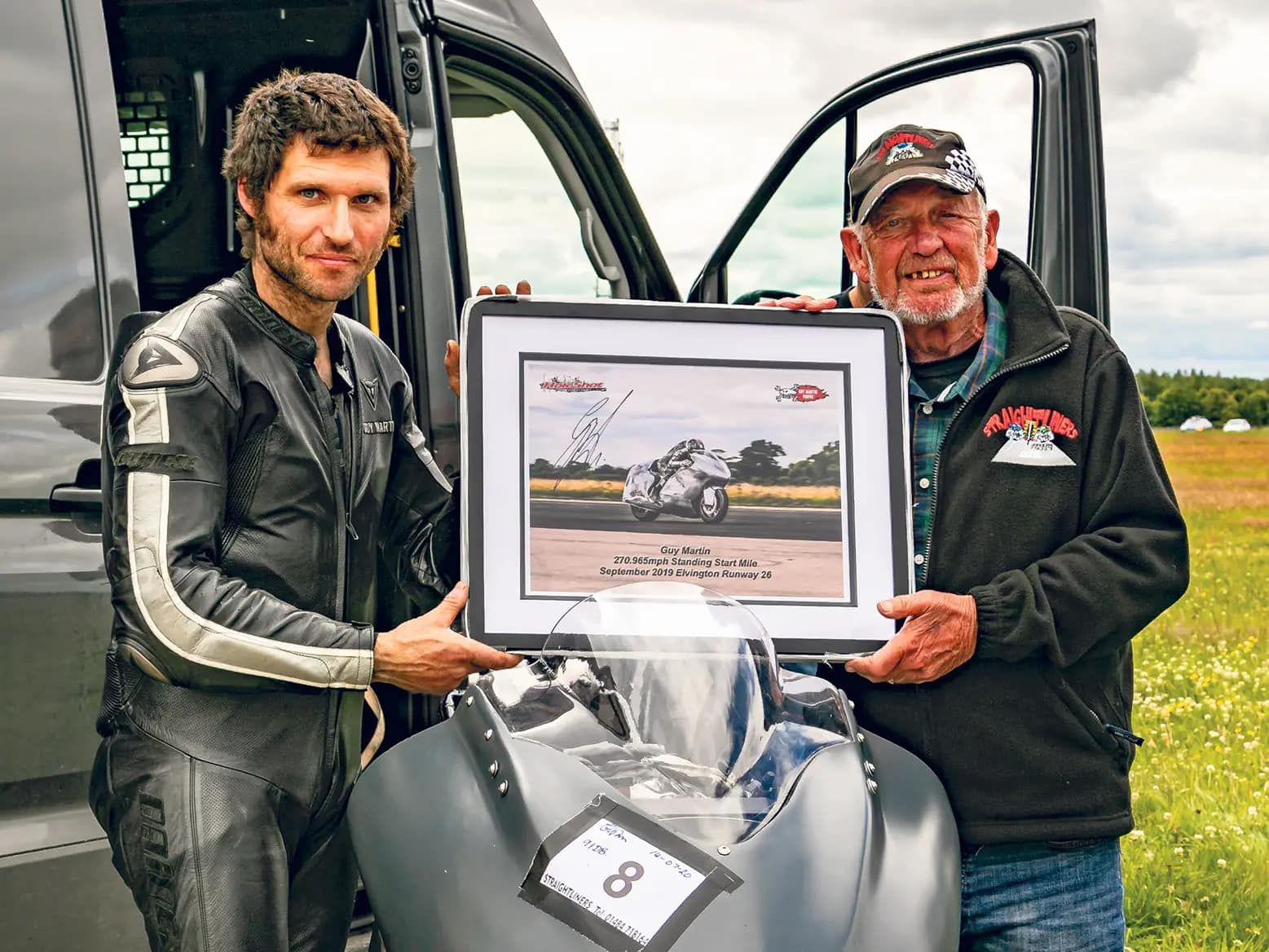 Guy Martin holding a framed images over his land speed record Suzuki Hayabusa.
