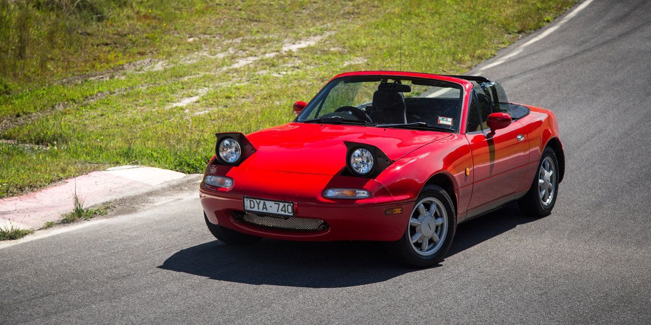 A First Gen Mazda MX-5 on a road. 