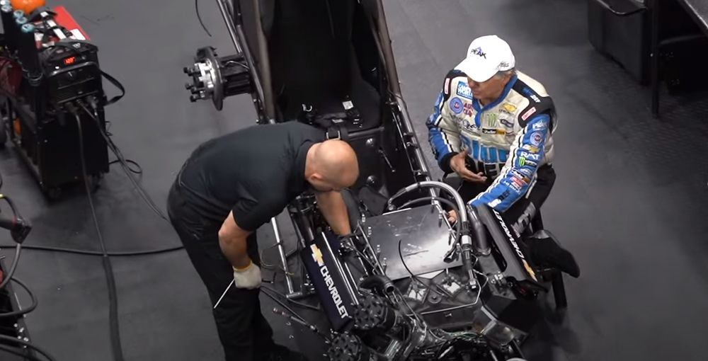 Drag racing legend John Legend examines top fuel vehicle with colleague