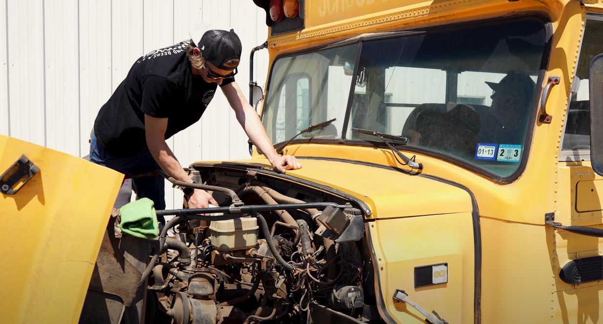Mechanic examines engine in an old schoolbus