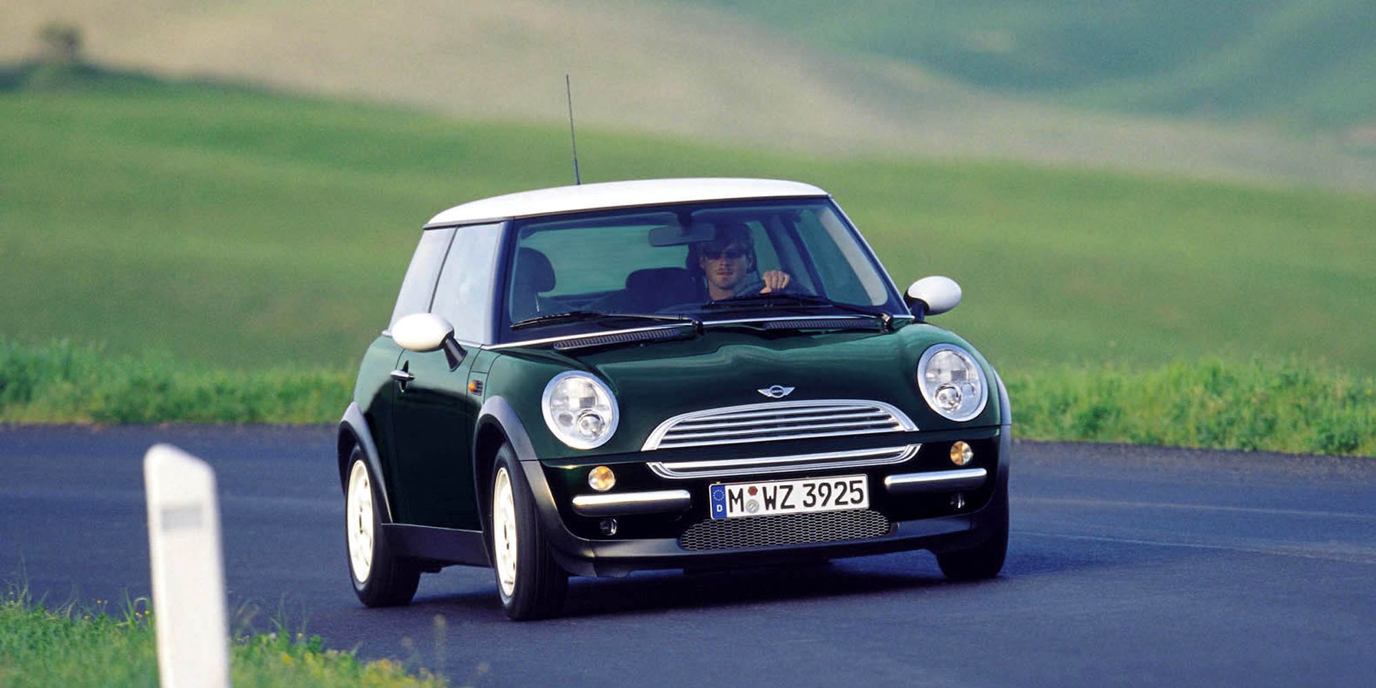 The front of a dark green Mini Hatch on the move