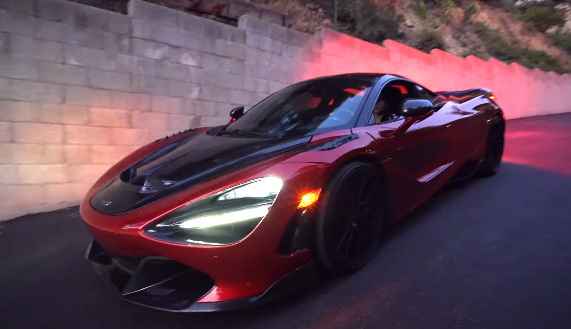 Red McLaren 720S supercar heads down hill during evening