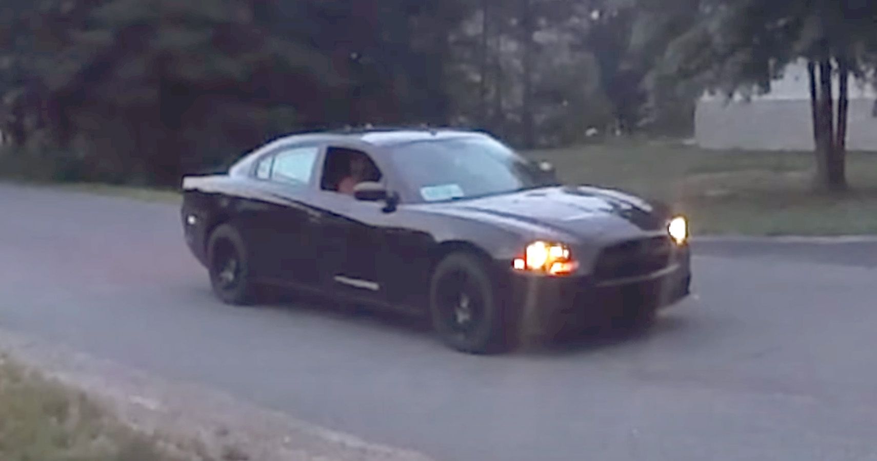 Black Dodge Charger police pursuit vehicle on rural road