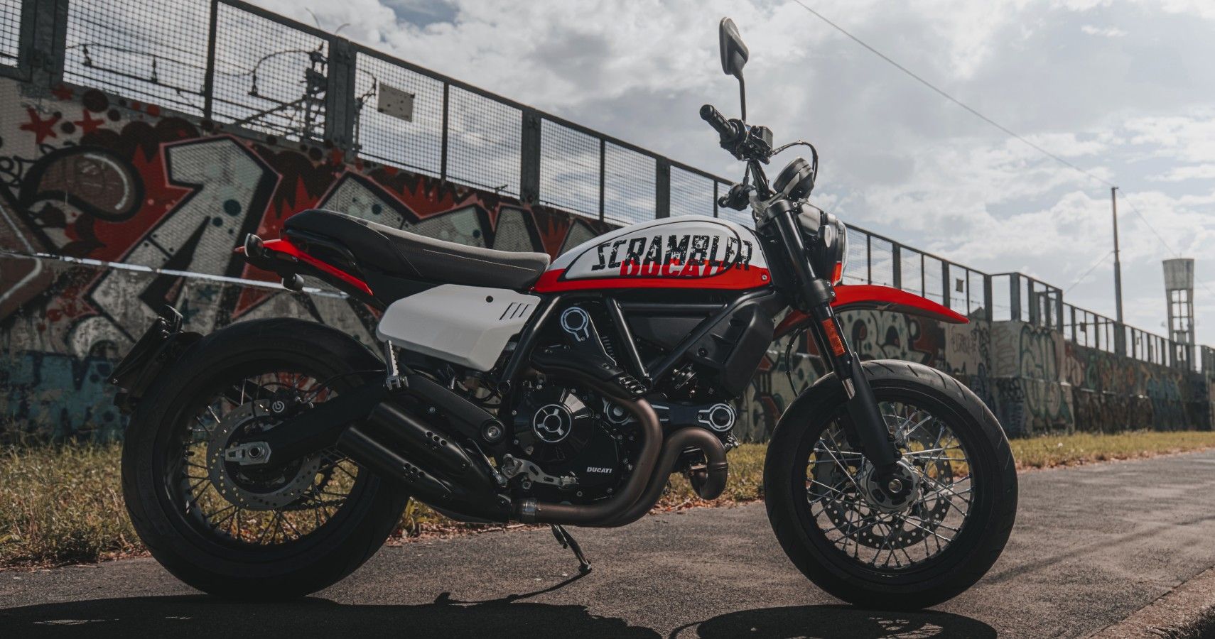 A 2022 Ducati Scrambler Urban Motard parked on a sidewalk.