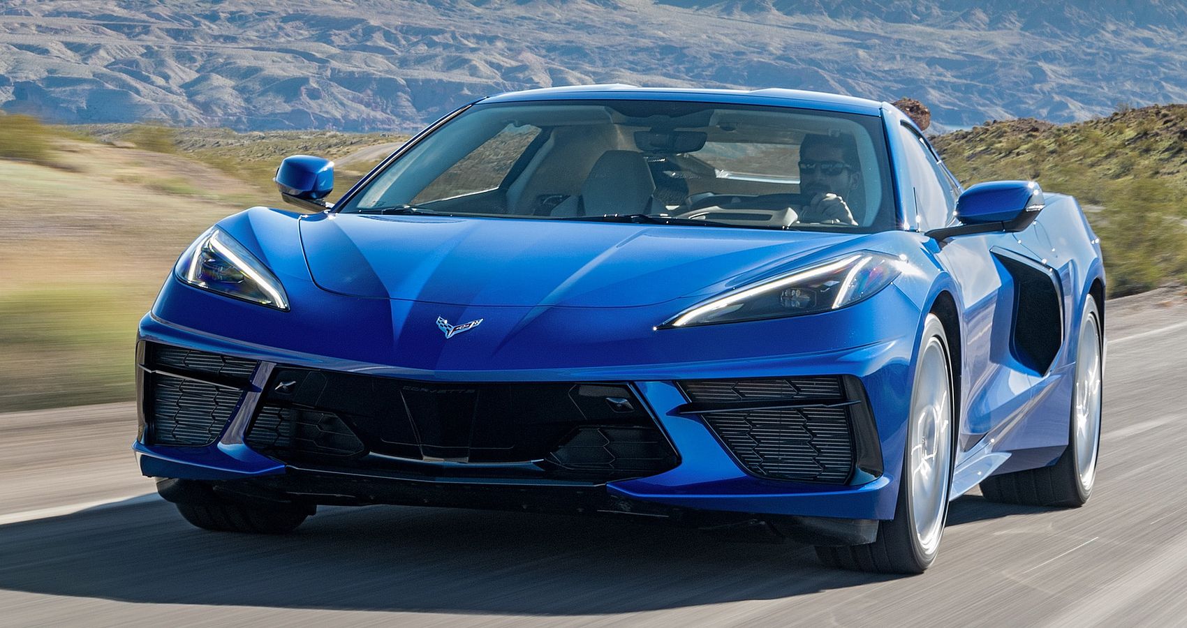 The front of a blue Corvette Stingray on the move