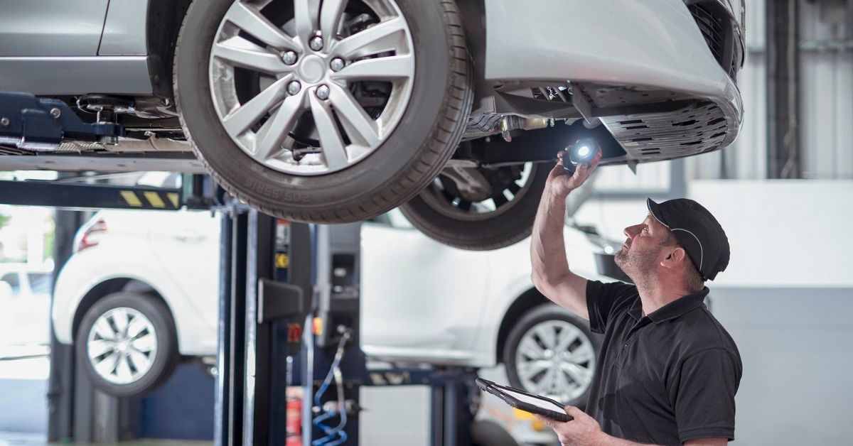 Man inspecting bottom of electric car