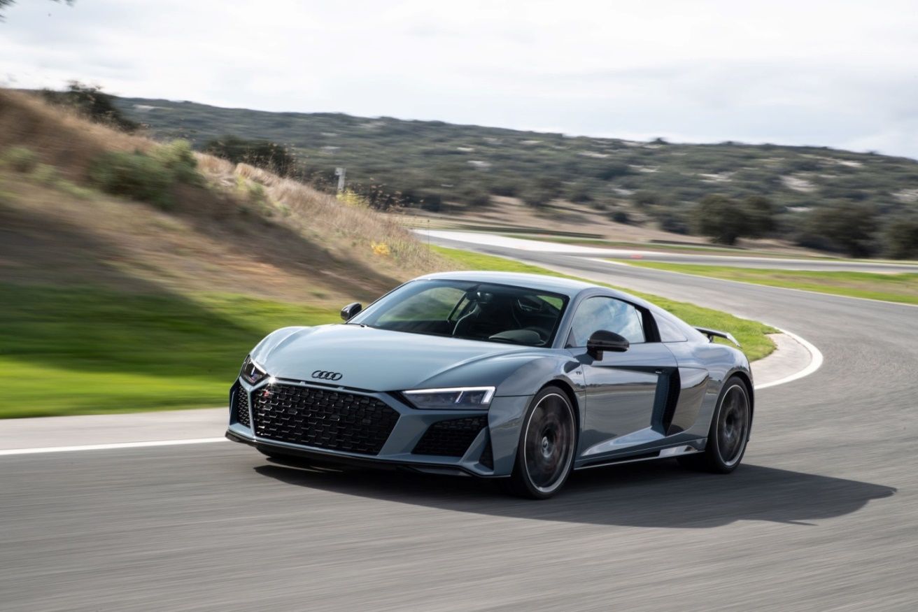 An Audi R8 going up a hill on the tarmac road.