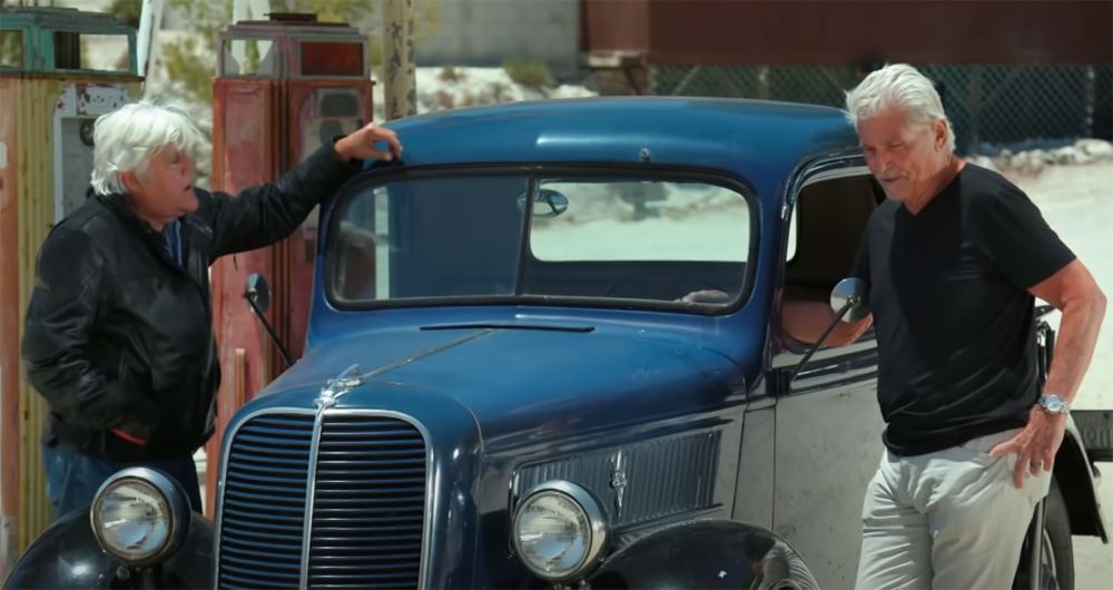 Jay Leno and James Brolin chat while leaning against a 1937 Ford pickup