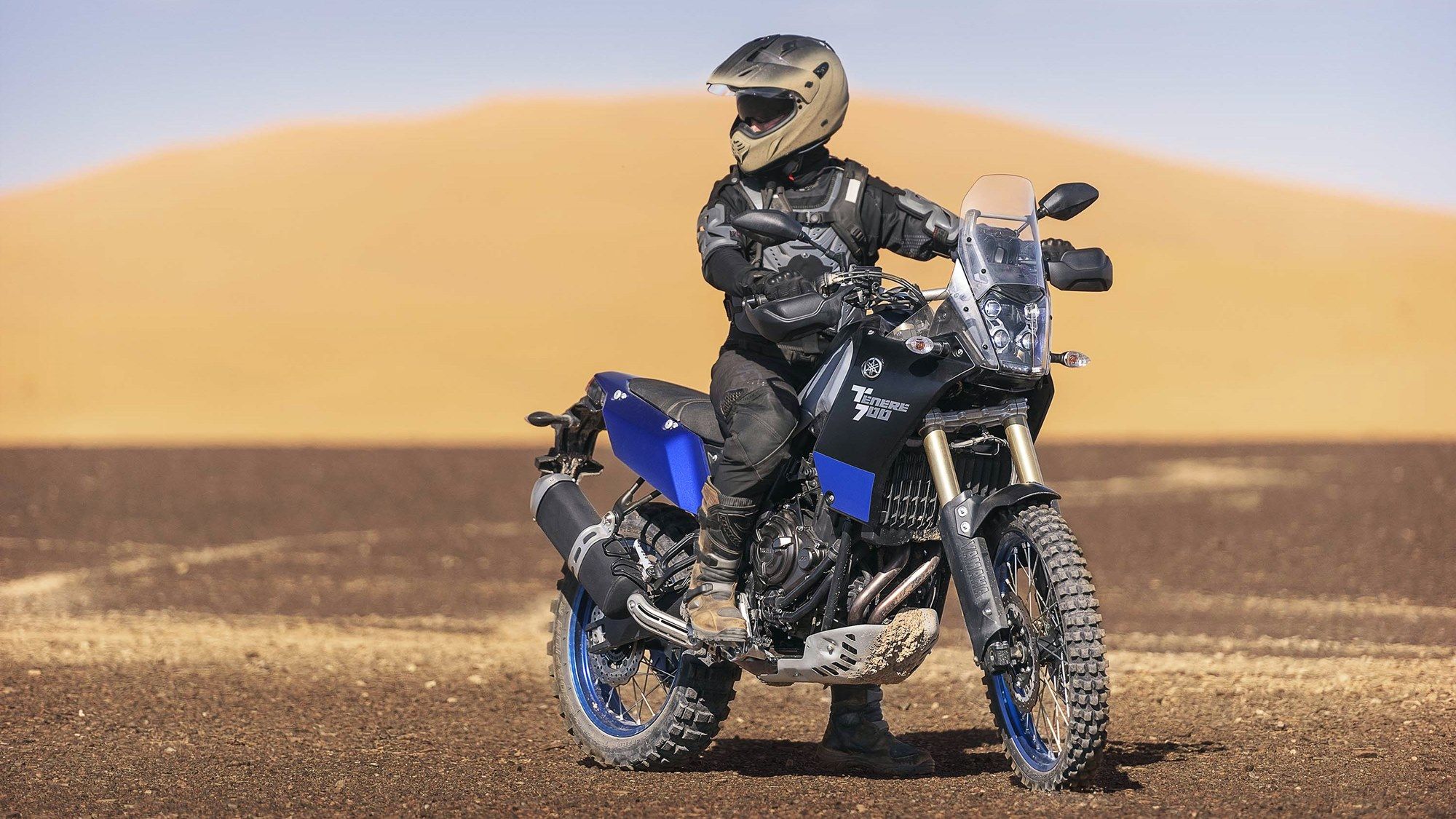 Person riding on a parked Yamaha Tenere 700 in desert