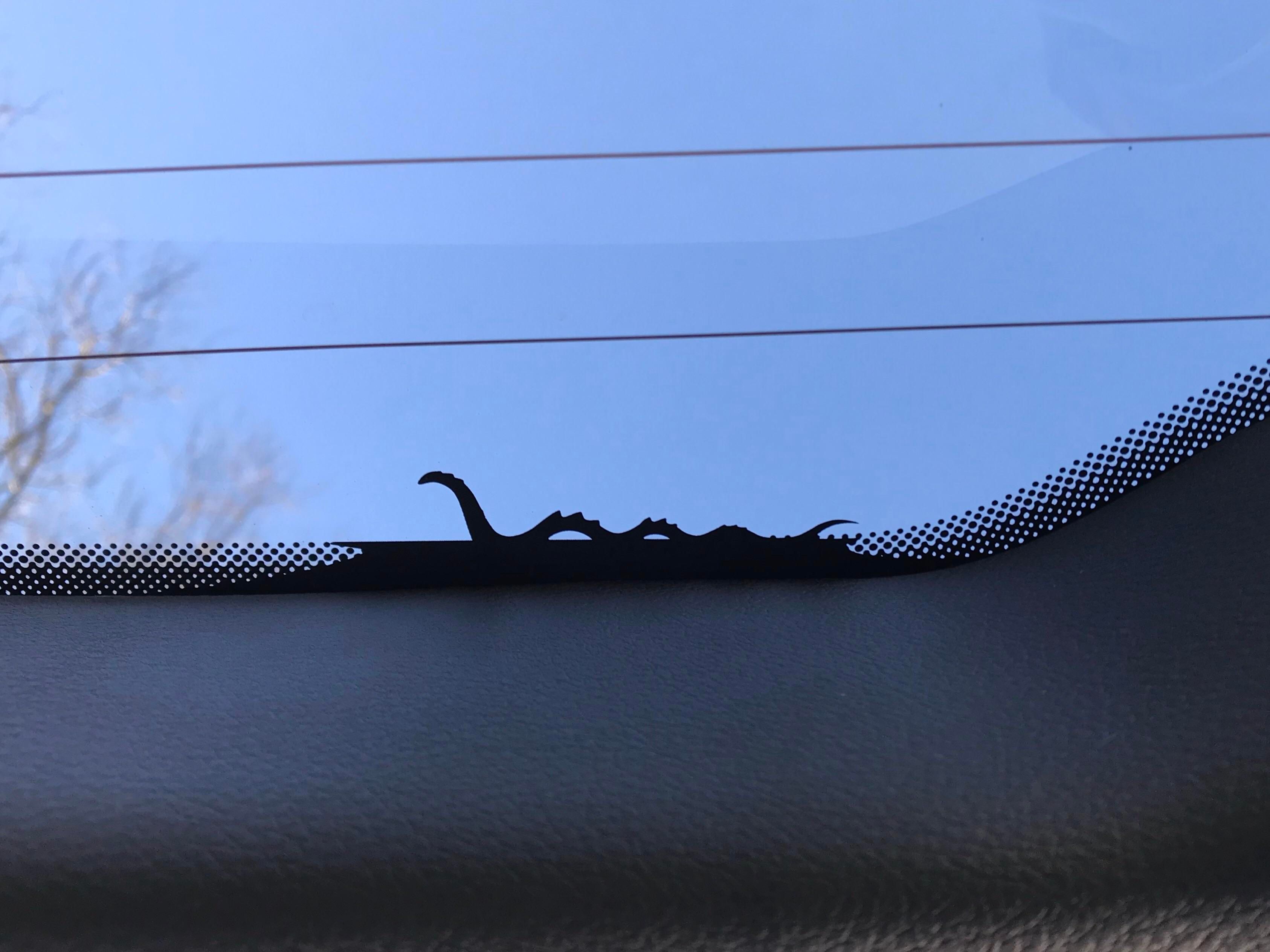Image shows a silhouette of a Loch Ness Monster on the rear windscreen of a Jeep Compass