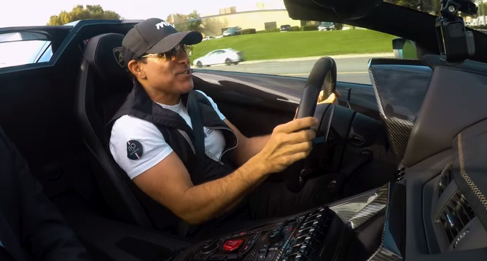 Manny Khoshbin behind the wheel of a white Lamborghini Aventador SVJ