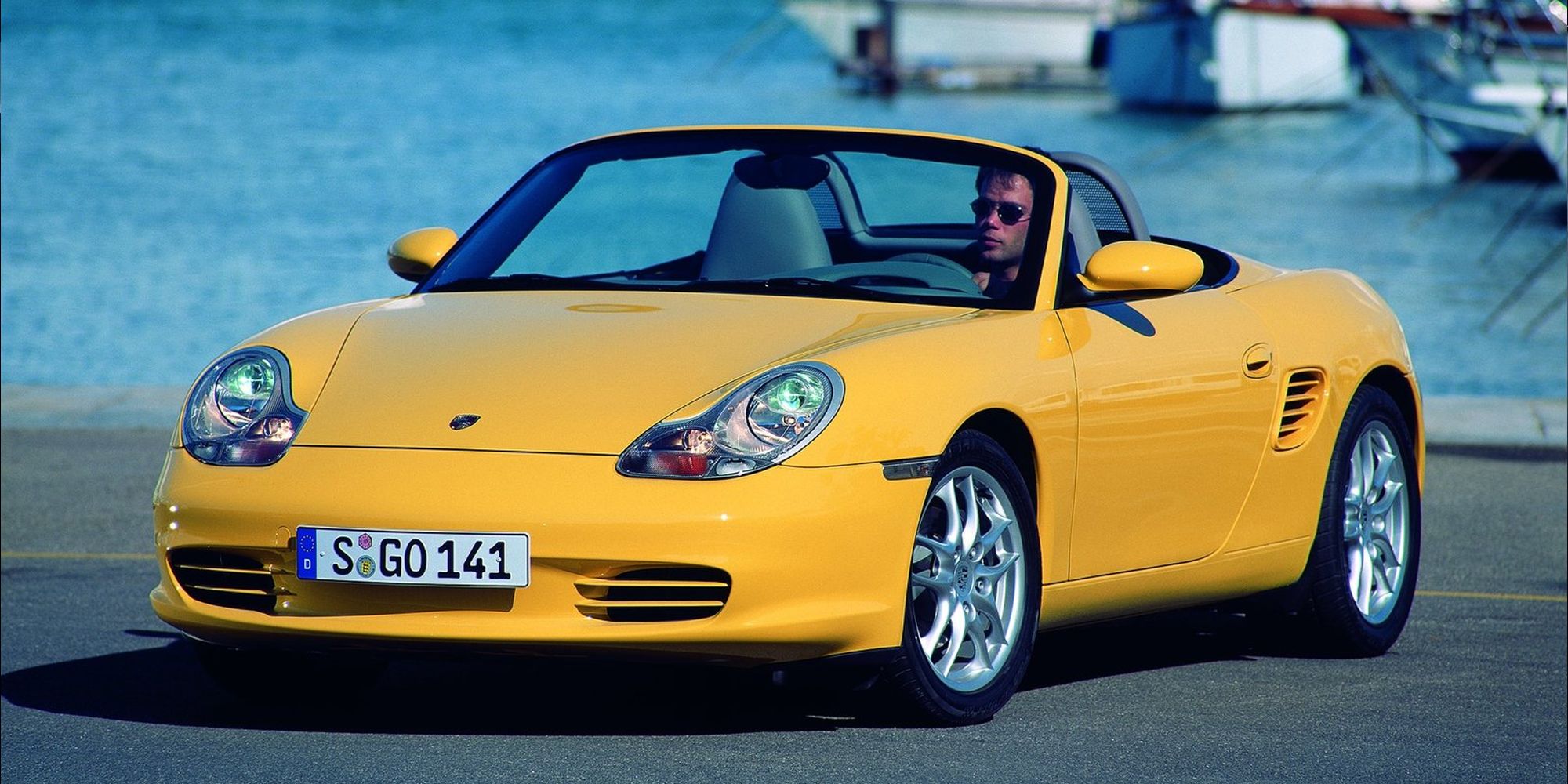 Front 3/4 view of a yellow Boxster, roof down