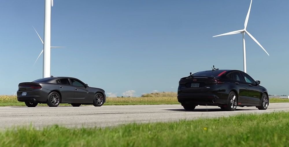 Dodge Charger and Ford Fusion line up on highway rear view