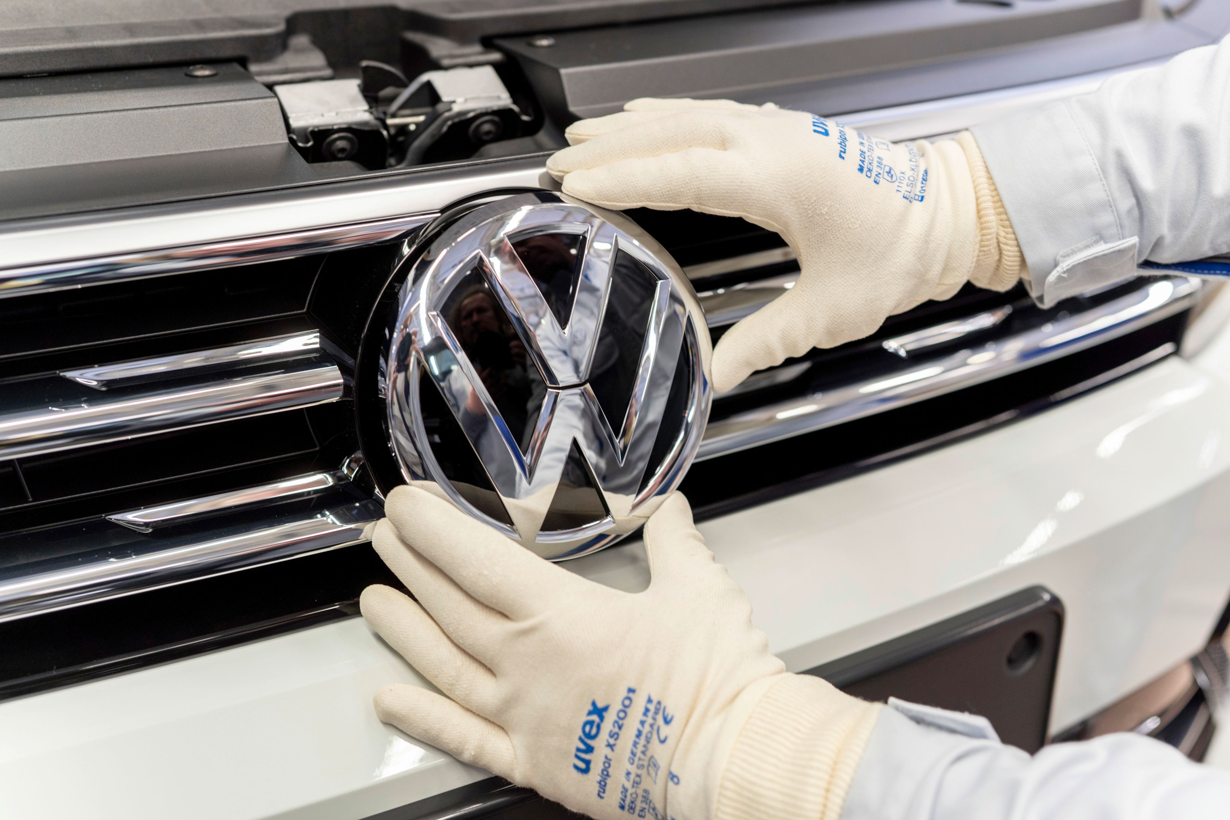 An employee puts the Volkswagen sign on a car.