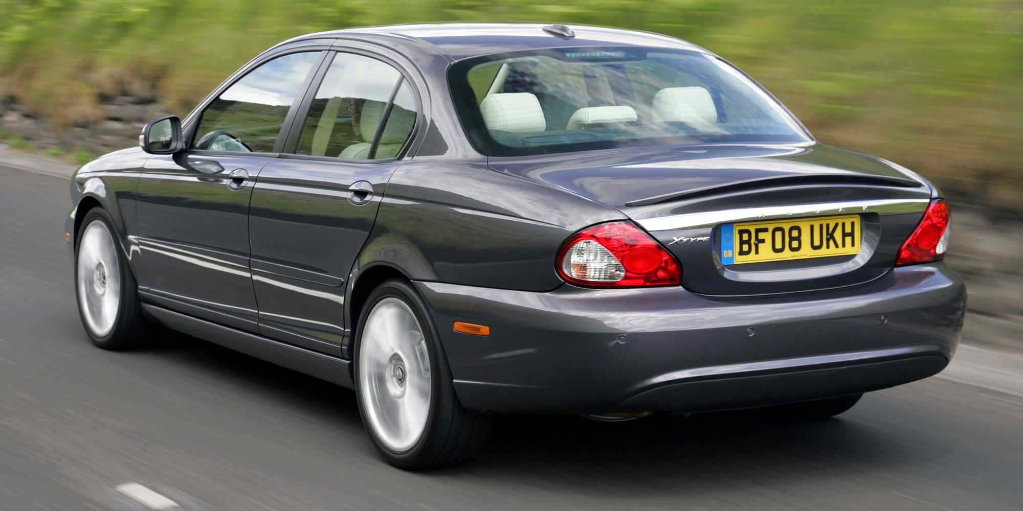 Rear 3/4 view of a gray X-Type sedan on the move