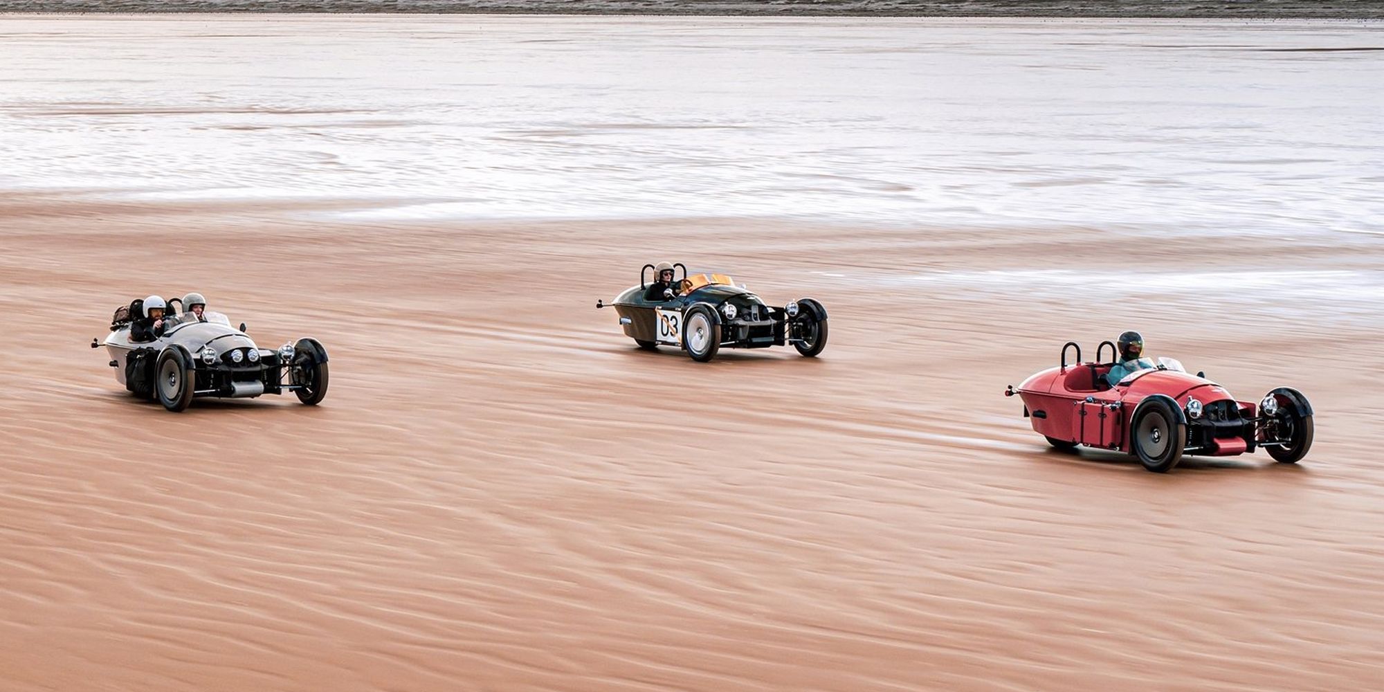 A trio of Super 3s speeding down wet sand, far apart