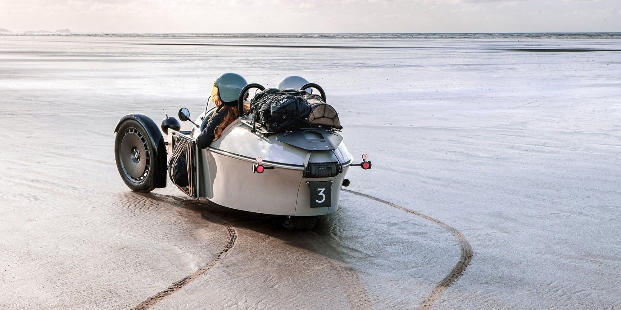 The rear of a gray Super 3 on wet sand