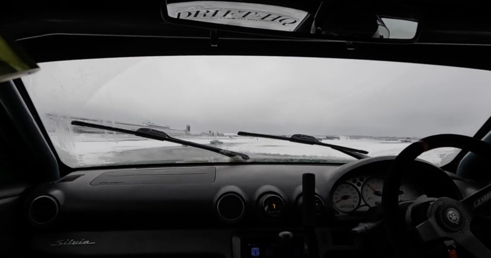 A cabin view looking out the dashboard of a Nissan Silvia driving through a heavy snow 