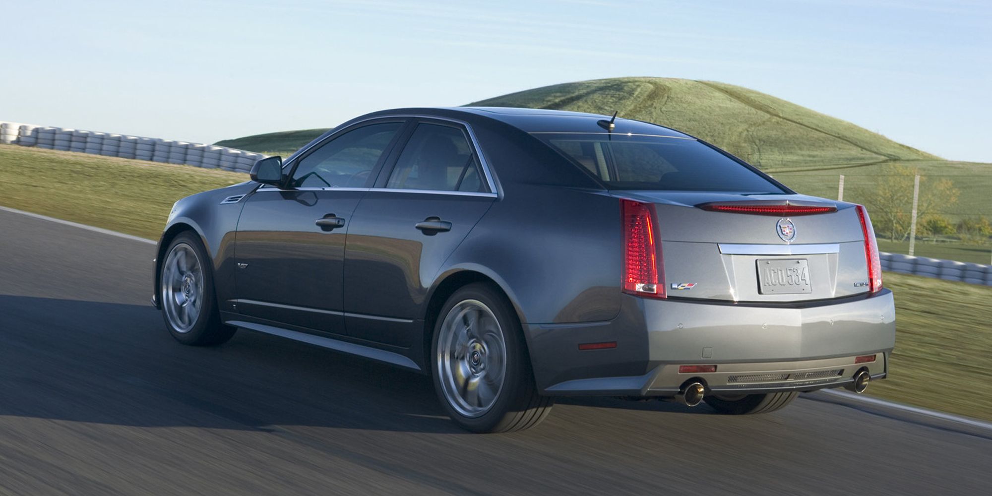 Rear 3/4 view of a silver CTS-V sedan on the move on a race track