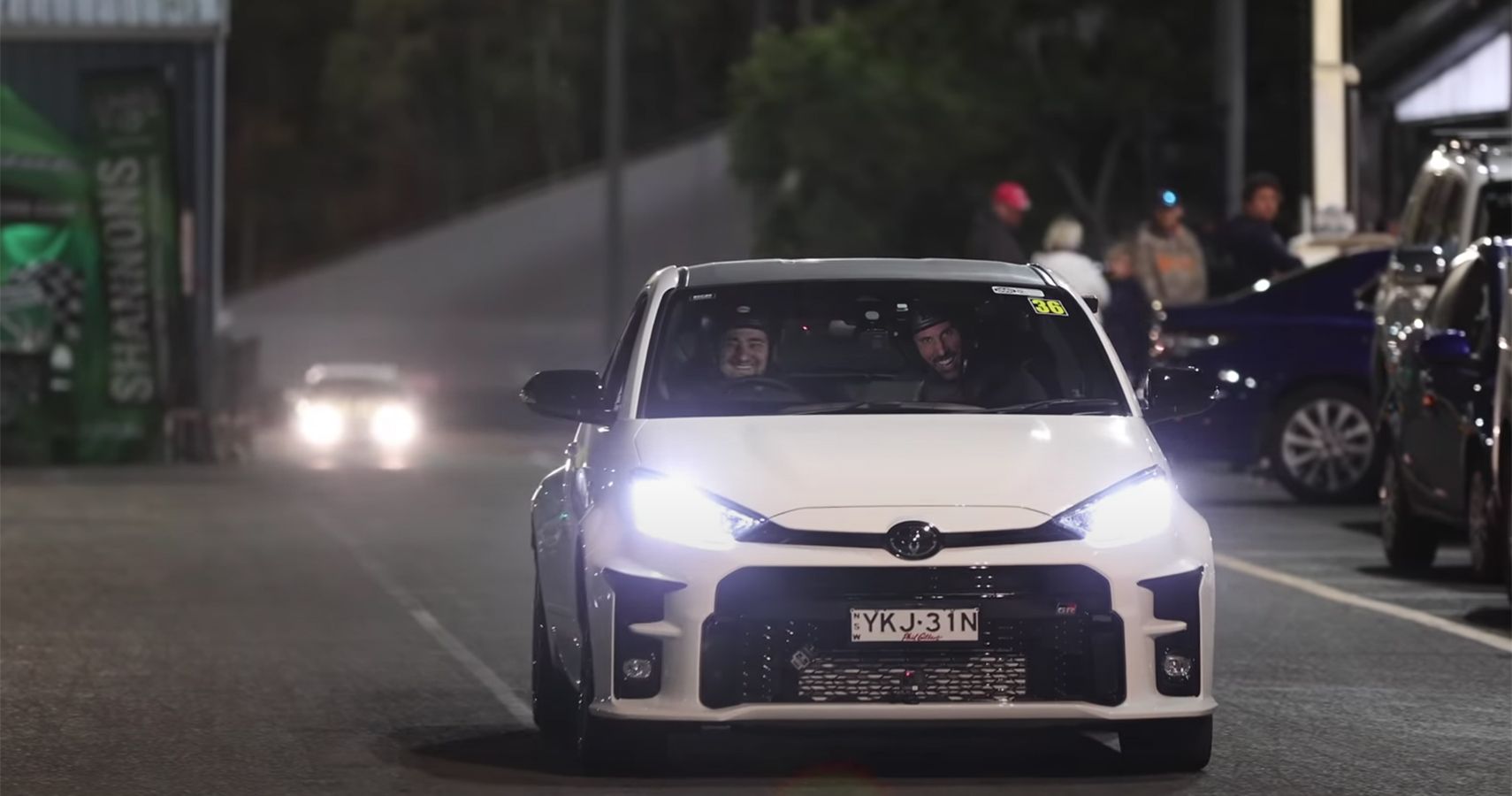 White Toyota GR Yaris at night, front view from distance on road