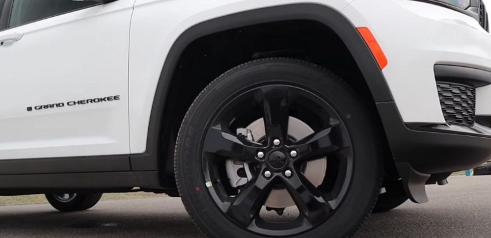 A black, five-spoke wheel of the 2022 Jeep Grand Cherokee L Altitude