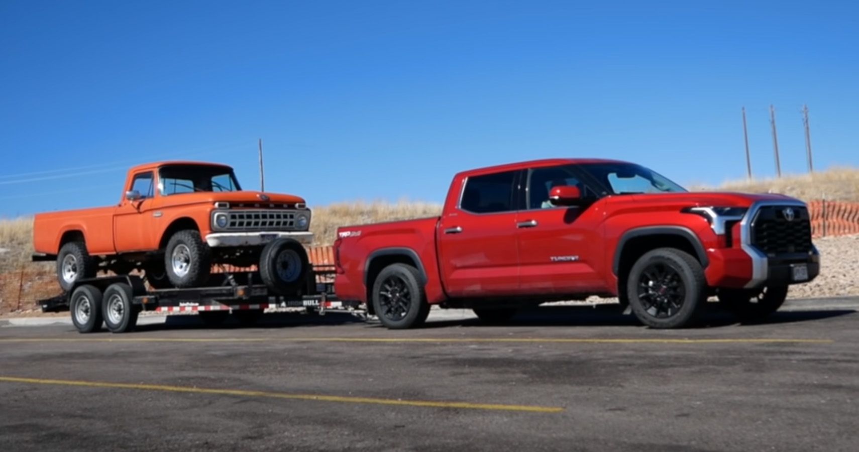 Red 2022 Toyota Tundra pulling an orange Ford F-100