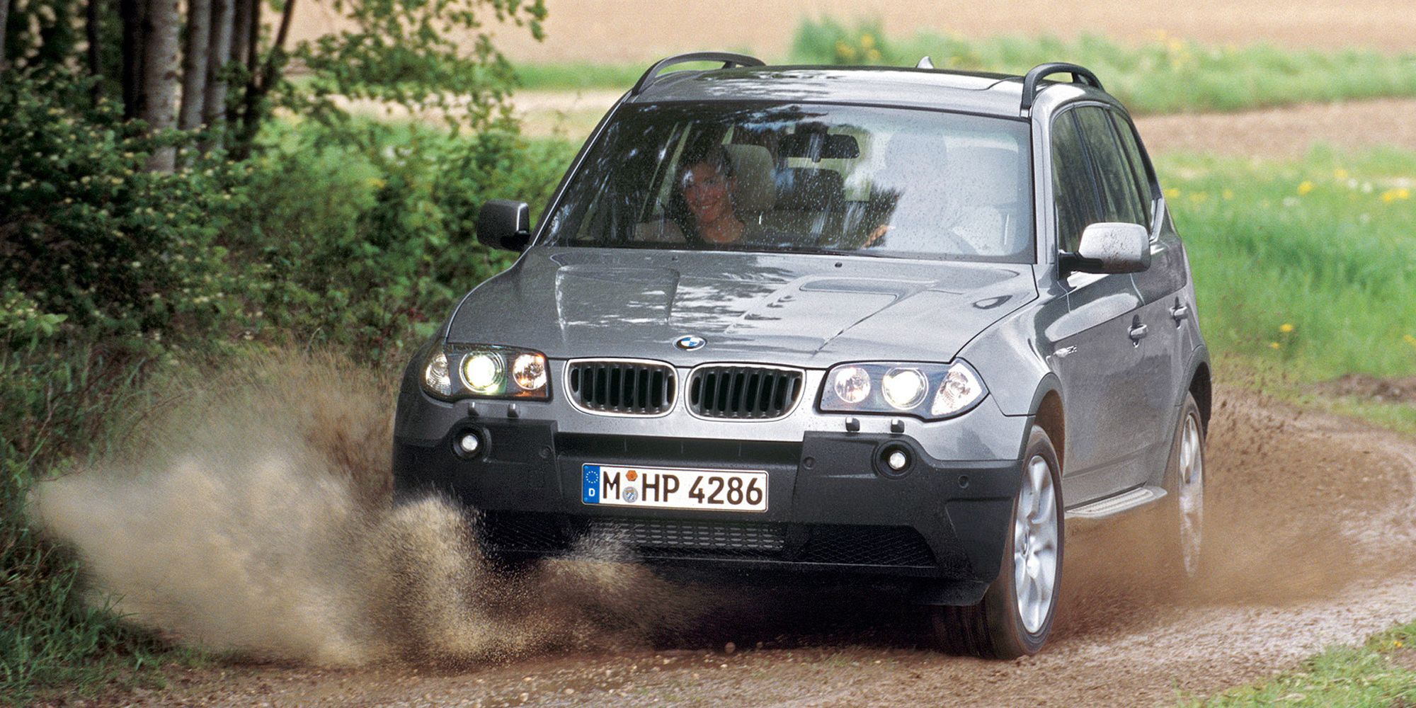 Front 3/4 view of a light gray E83 X3 attempting to off-road