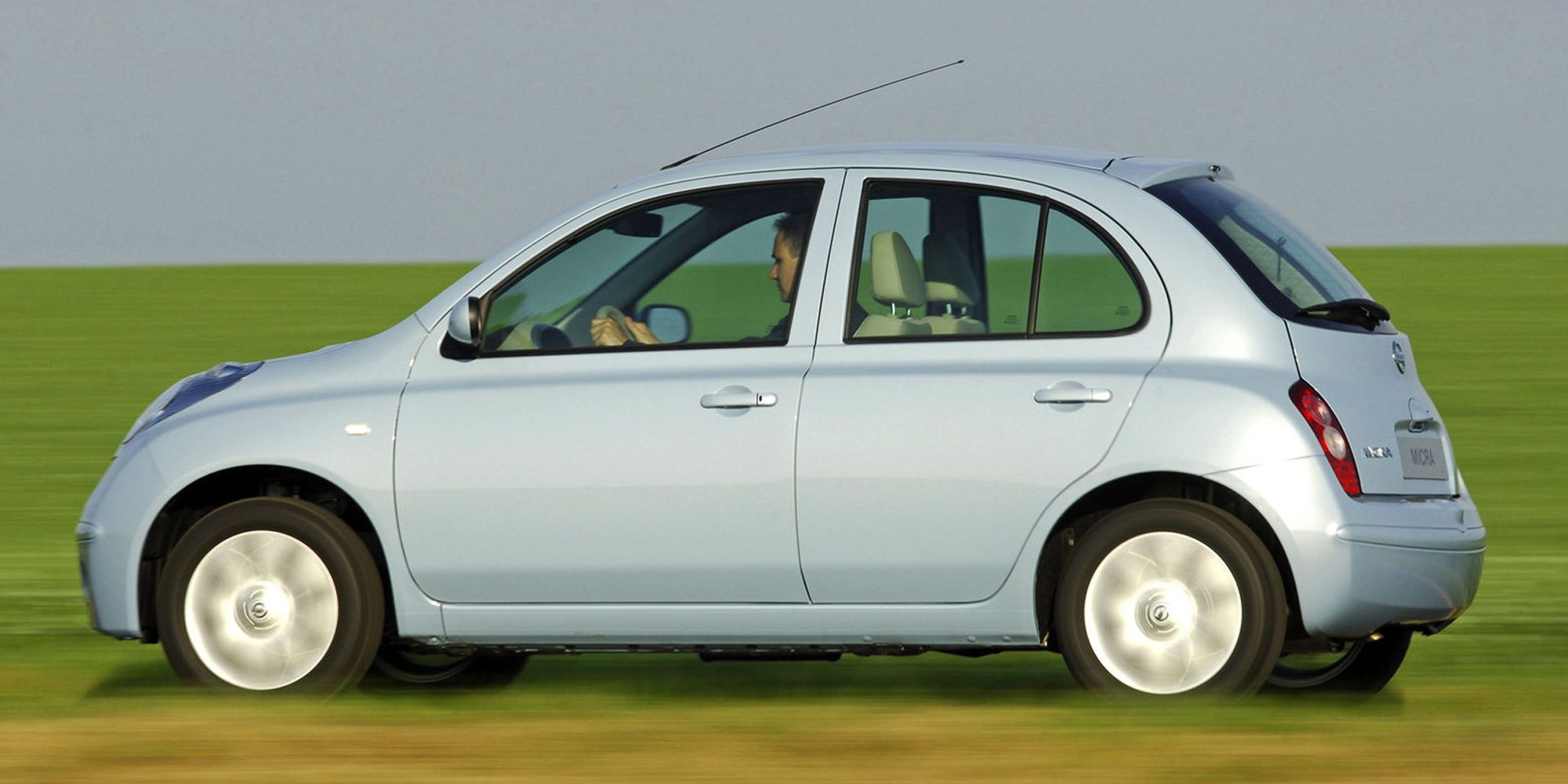 Rear 3/4 view of a sky blue Micra on the move