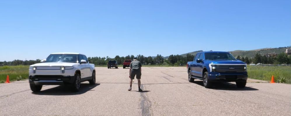 Rivian R1T vs Ford F-150 Lightning drag race, front profile view of both, at starting line