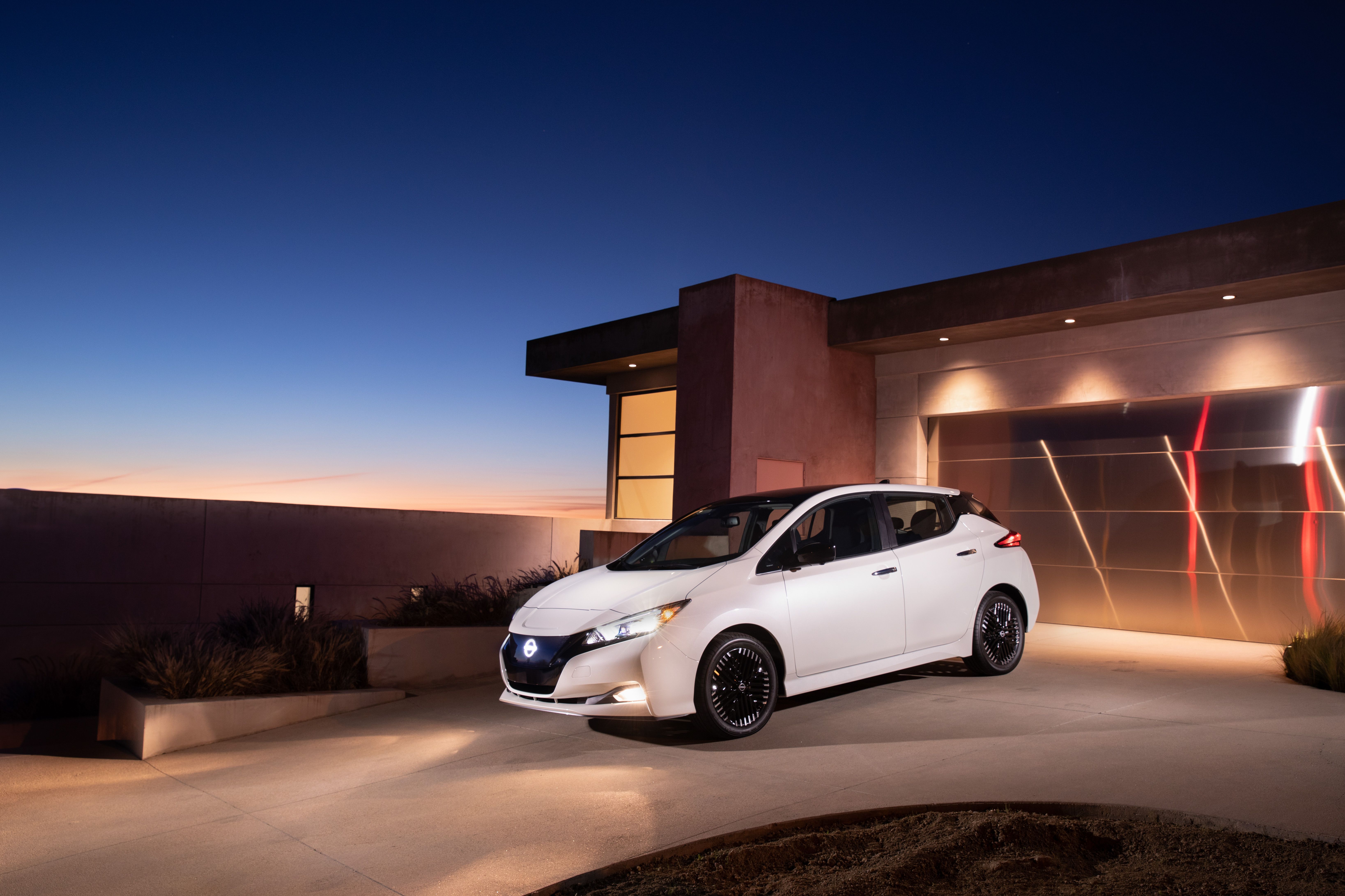 The 2023 Nissan Leaf in front of a garage. 