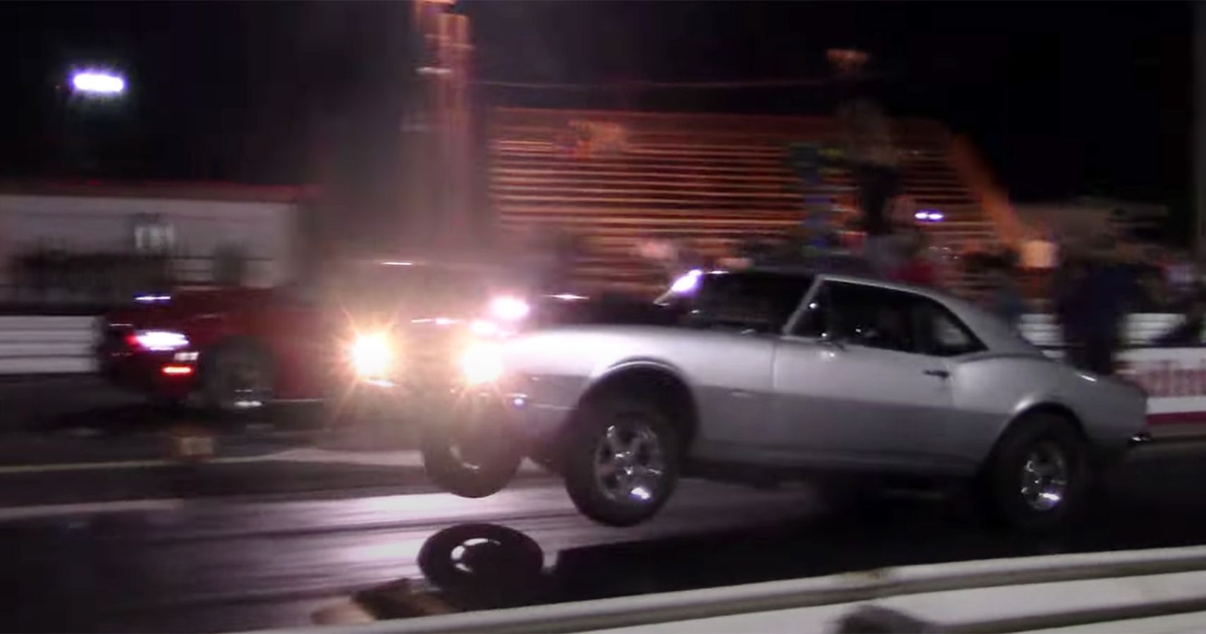 Silver 1967 SBC Chevrolet Camaro in drag race, night, view from distance at side