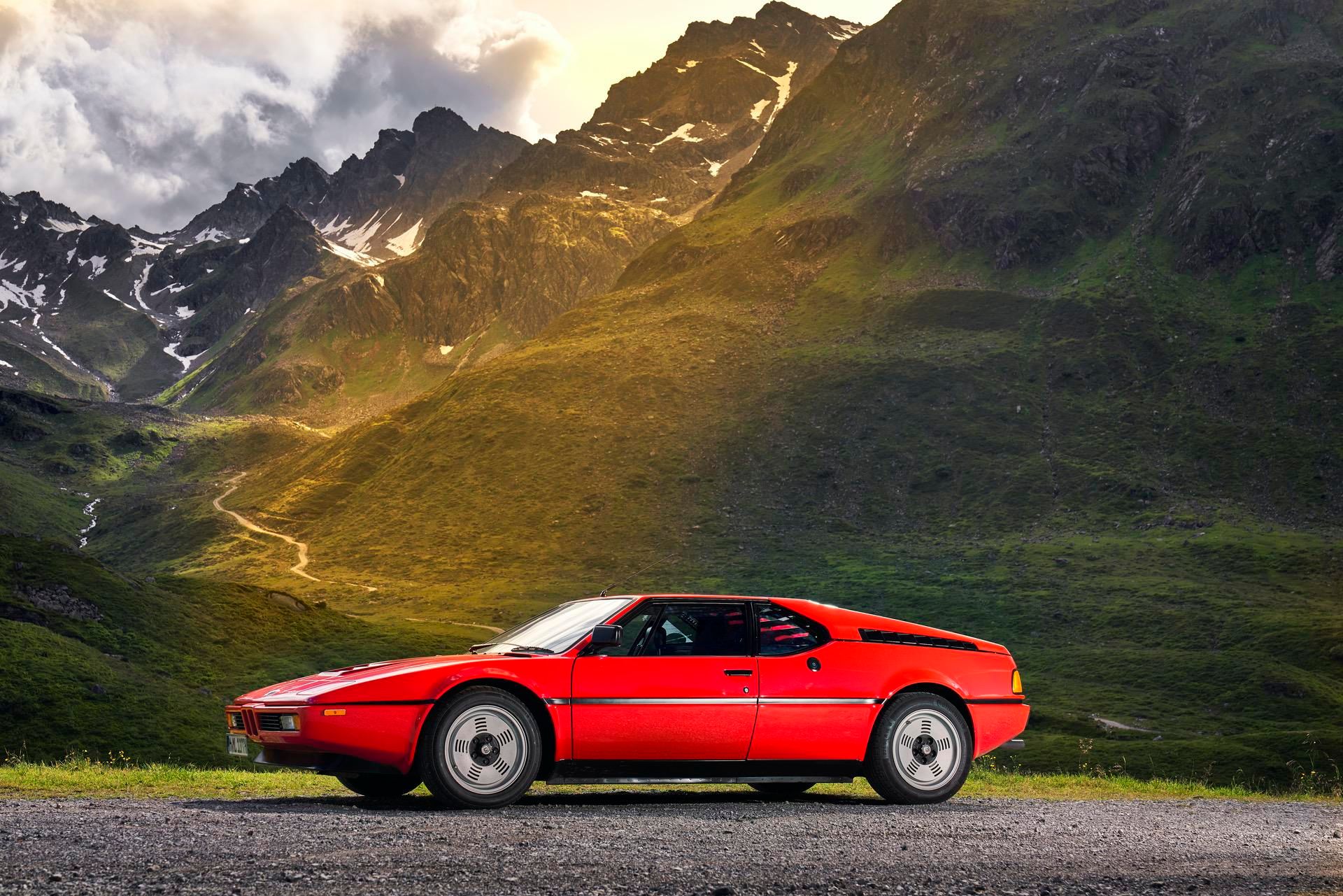 BMW-M1-red-supercar parked in front of mountains side view
